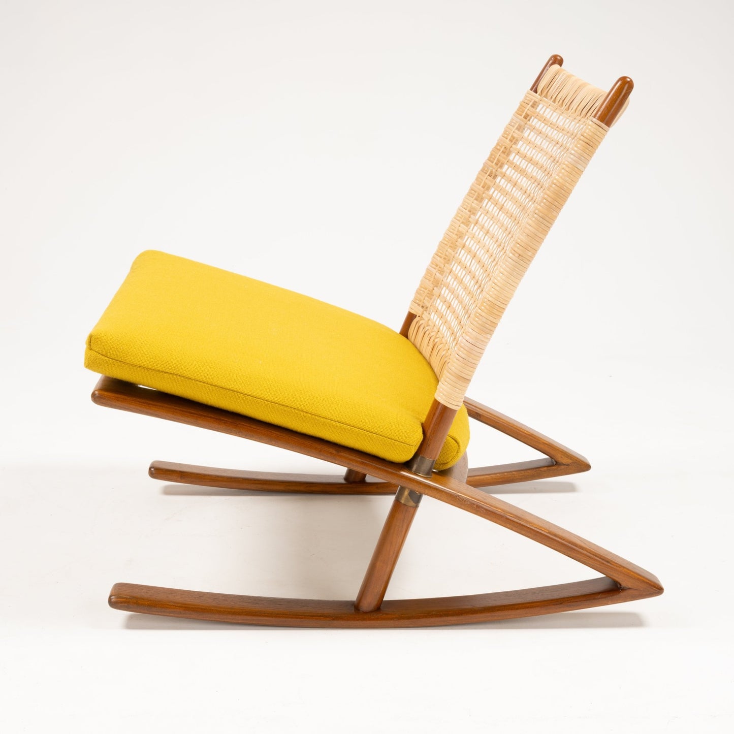 Side perspective of Fredrik Kayser Model 599 rocking chair with woven backrest, teak frame, and yellow wool cushion