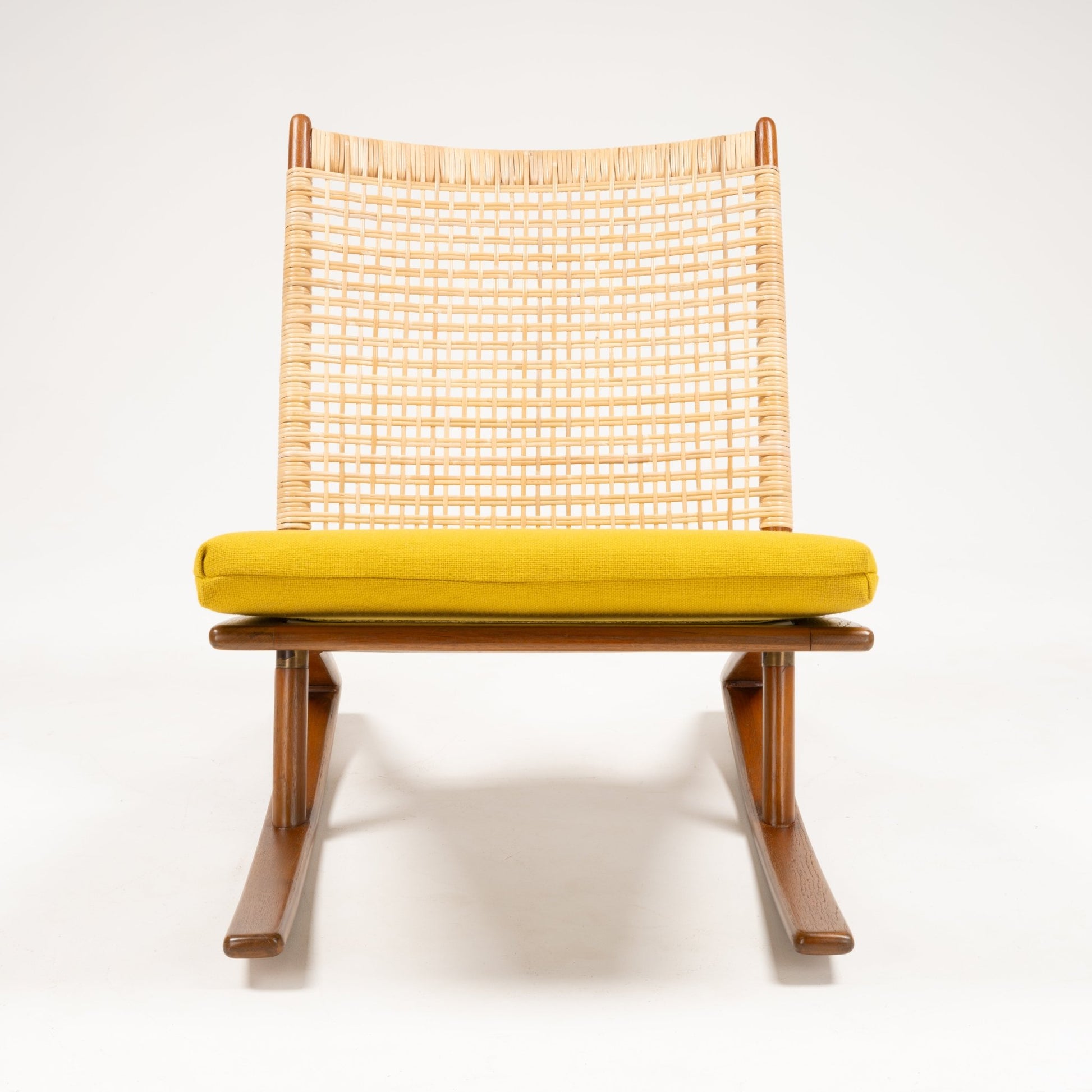Front view of Fredrik Kayser Model 599 rocking chair with woven backrest, teak frame, and mustard yellow wool cushion