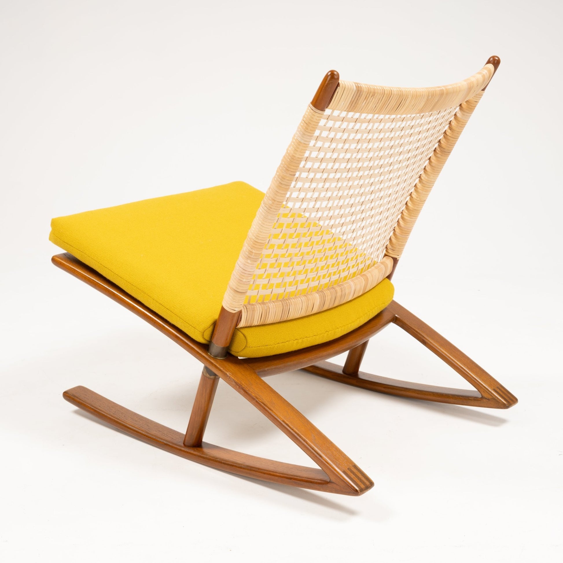Angled rear view of Fredrik Kayser Model 599 rocking chair with woven cane backrest, teak frame, and vibrant yellow cushion