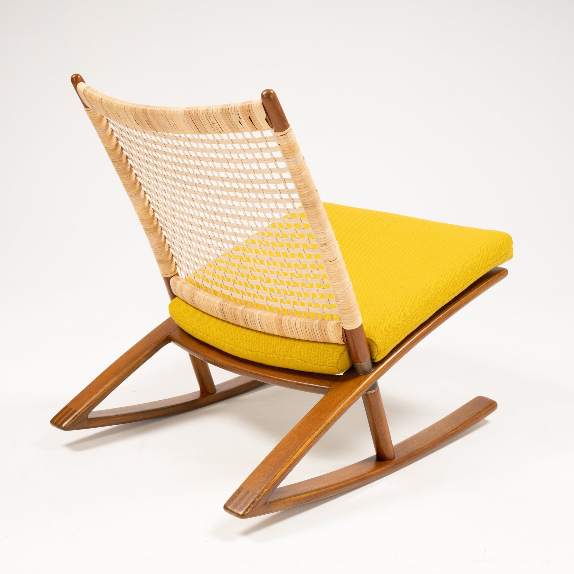 Rear angle of Fredrik Kayser Model 599 rocking chair with woven backrest, teak frame, and bright yellow wool cushion