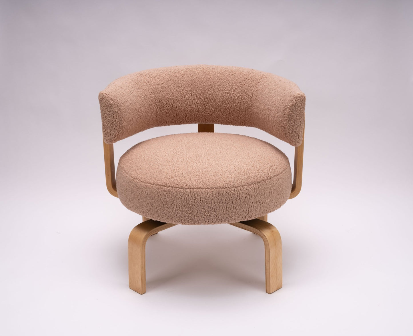 Fridene swivel chair by Carina Bengs with curved backrest, beechwood frame, and plush faux sheepskin upholstery