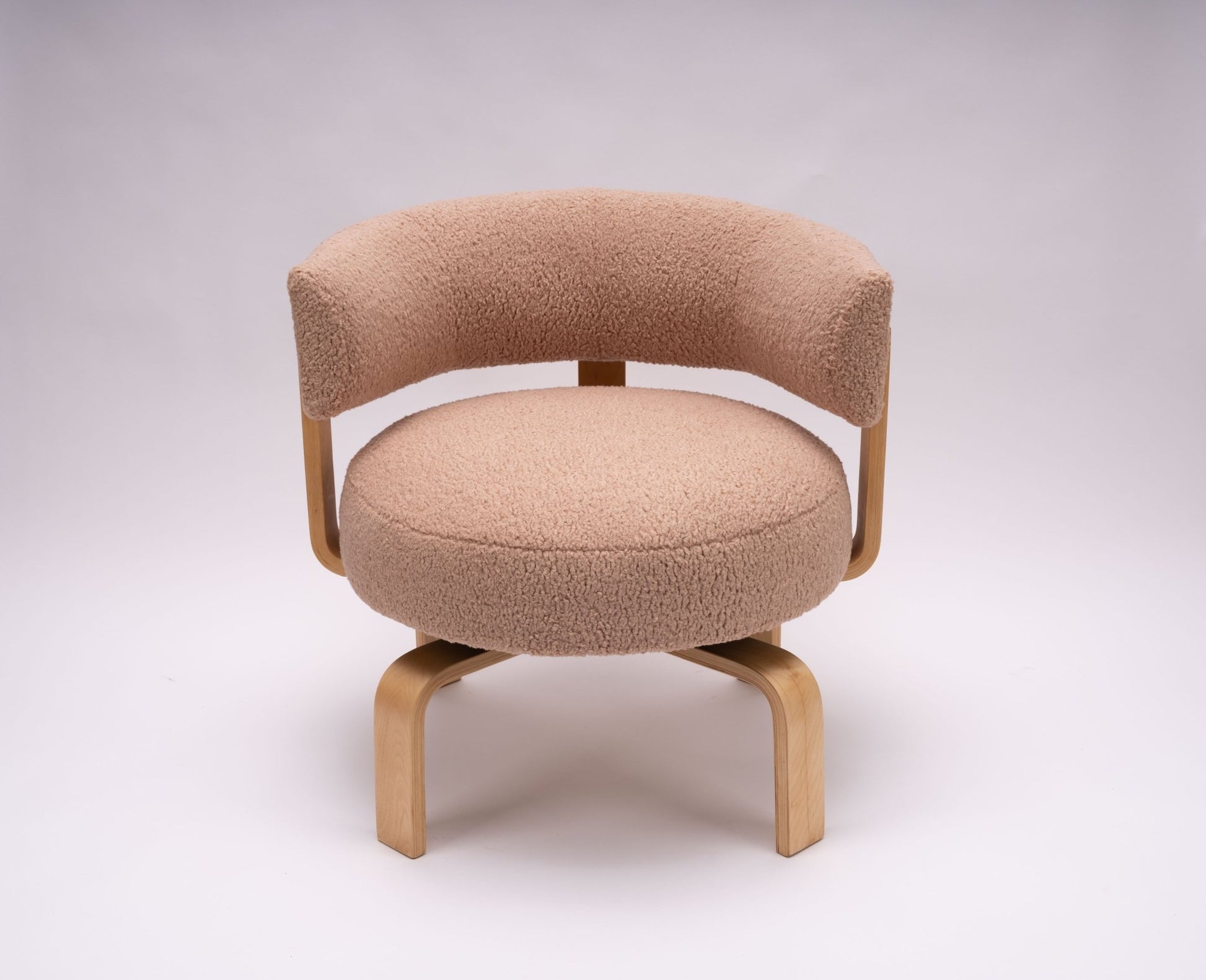 Fridene swivel chair by Carina Bengs with curved backrest, beechwood frame, and plush faux sheepskin upholstery