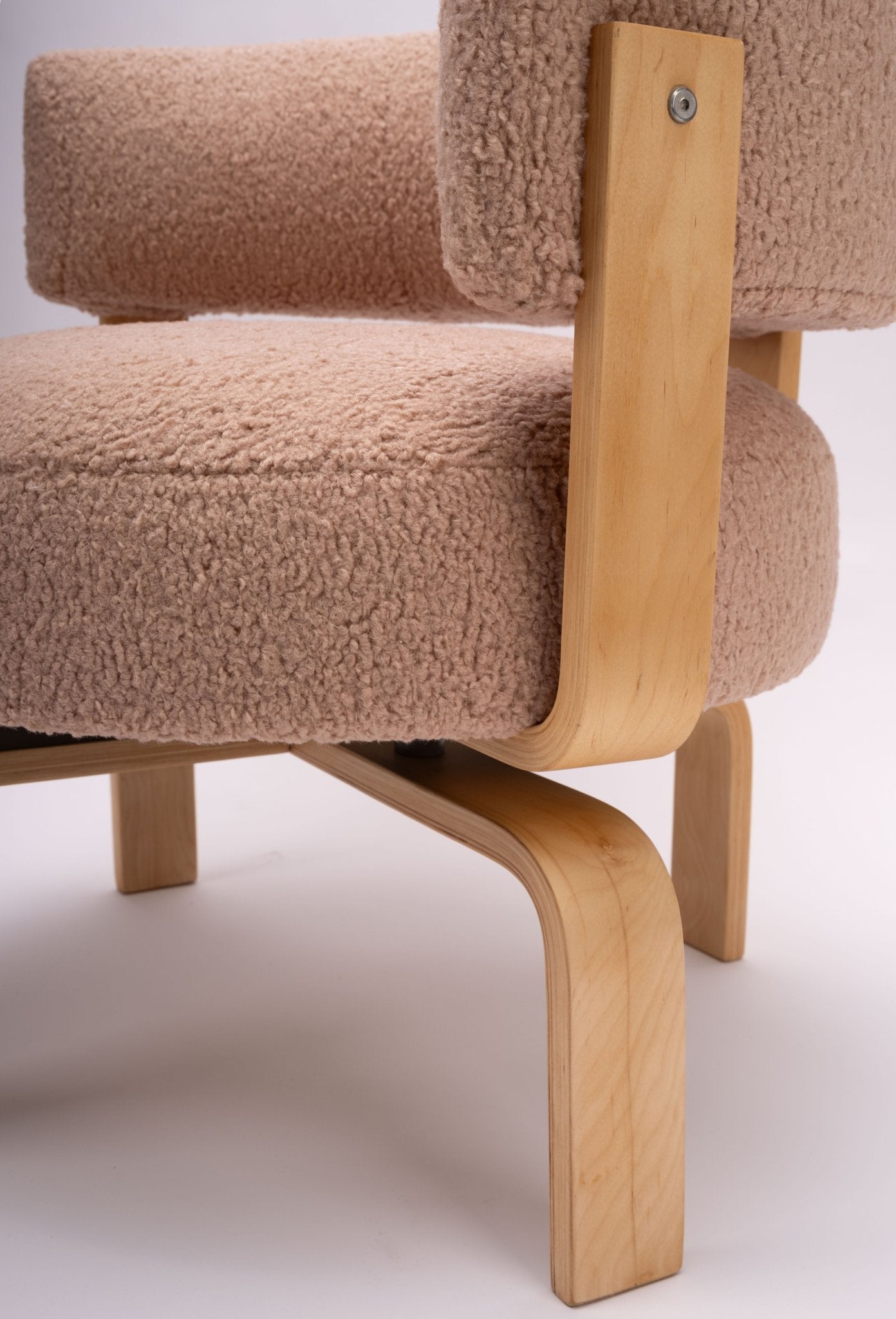 Close-up of mid-century modern Fridene swivel chair with beige faux sheepskin upholstery and bent beechwood frame.