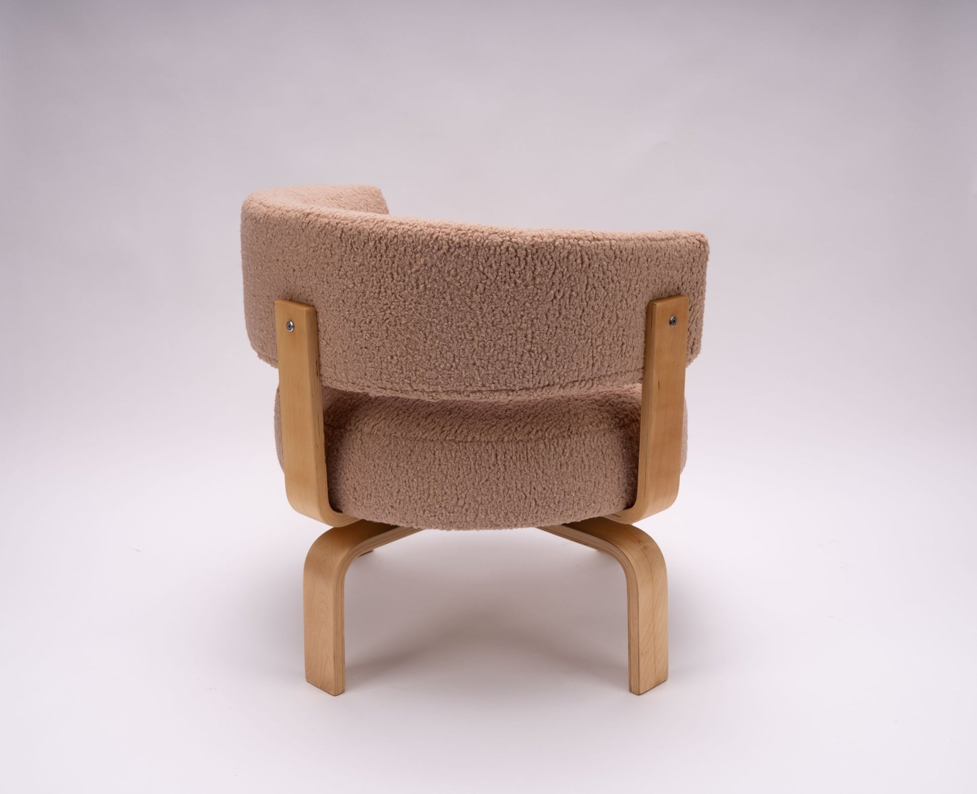 Swiveling Fridene armchair by Carina Bengs with beechwood frame and maharam faux sheepskin upholstery shown from back.