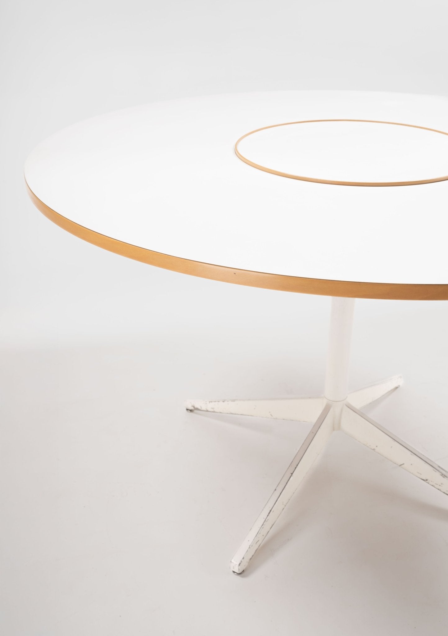 Circular mid-century modern dining table with white laminate top, wooden edge, Lazy Susan center, and white metal base.