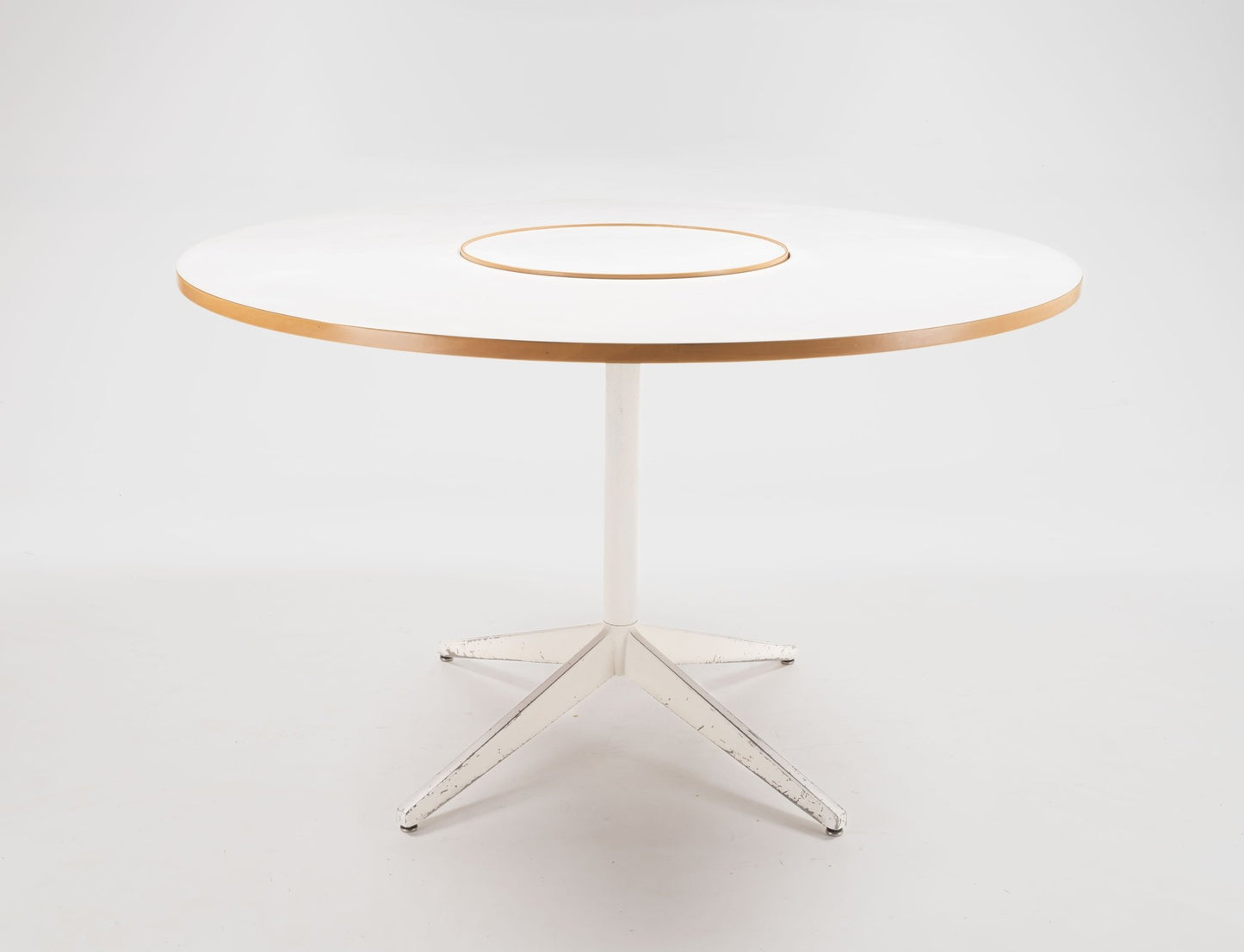 George Nelson 1950s circular dining table with white laminate top and central rotating Lazy Susan on white metal base.