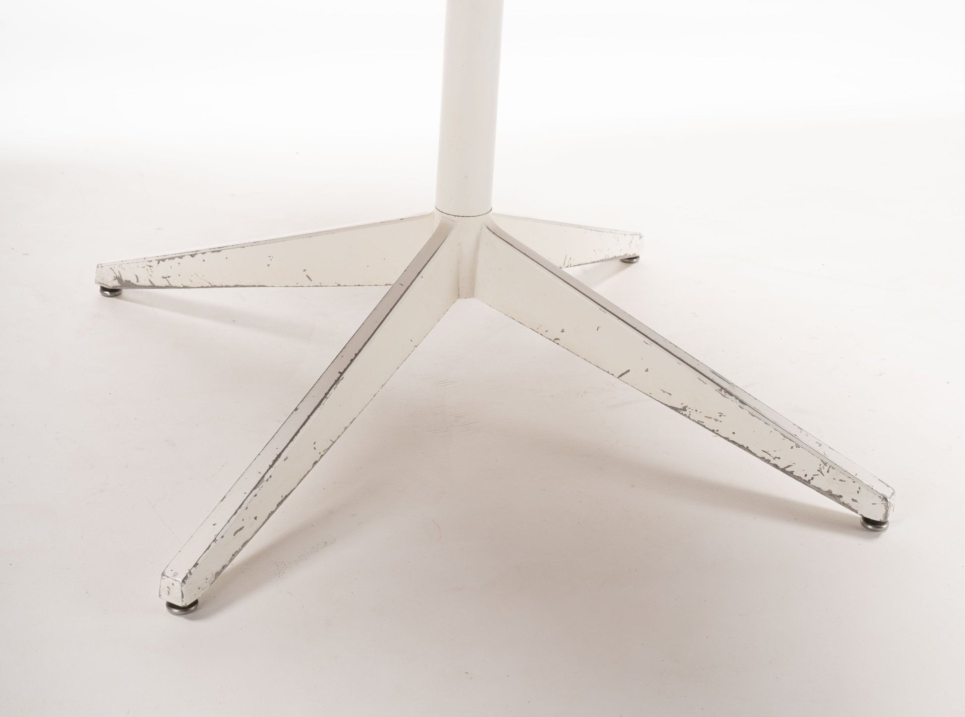 White powder-coated metal star-shaped base of mid-century modern George Nelson Lazy Susan table.