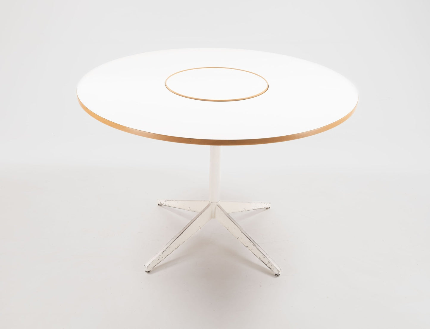 George Nelson 1950s circular dining table with white laminate top, central Lazy Susan, and white metal base.