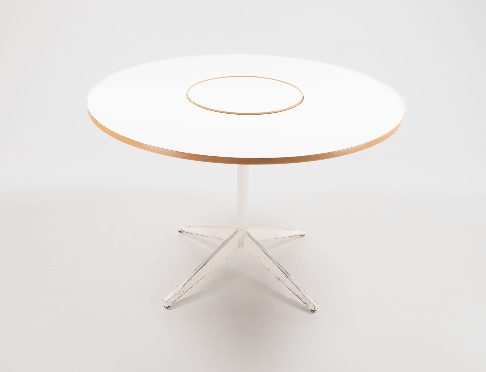 George Nelson 1950s circular dining table with white laminate top, central Lazy Susan, and white metal base.