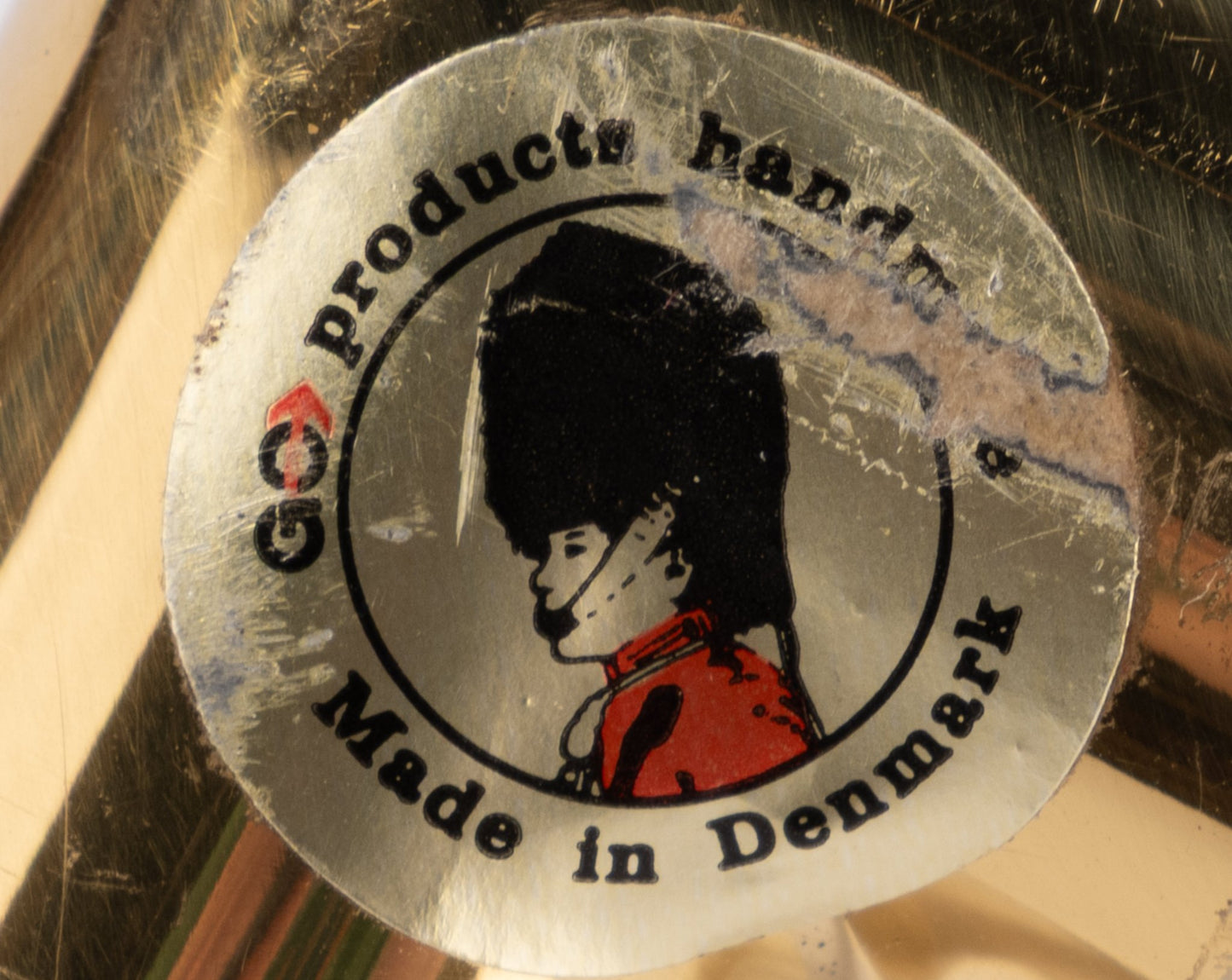 Close-up of vintage Go Products label with Danish guard illustration on polished brass 1970s candle holder made in Denmark