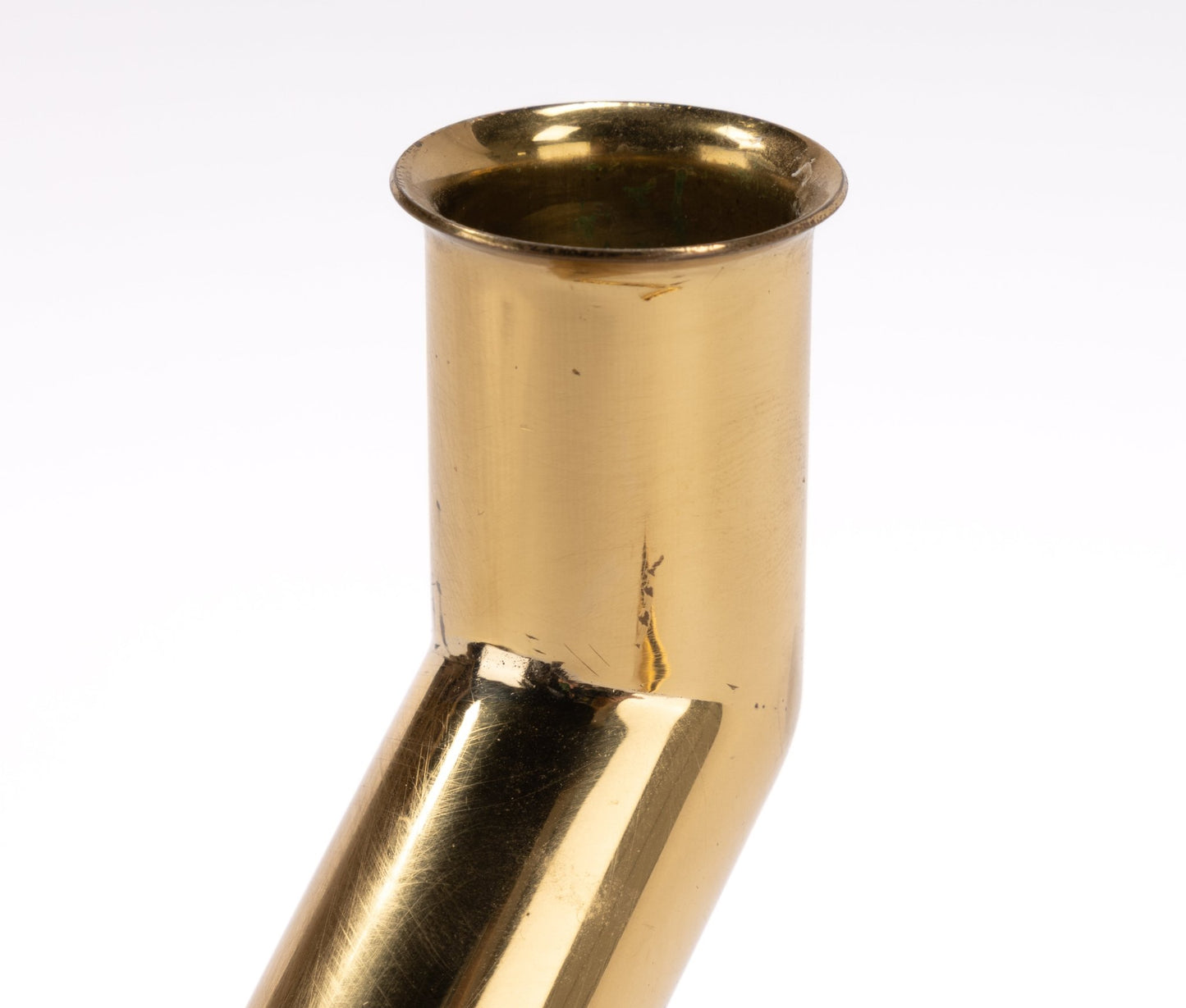 Close-up of polished brass Go Products 1970s Danish candle holder with angled tubular design on white background