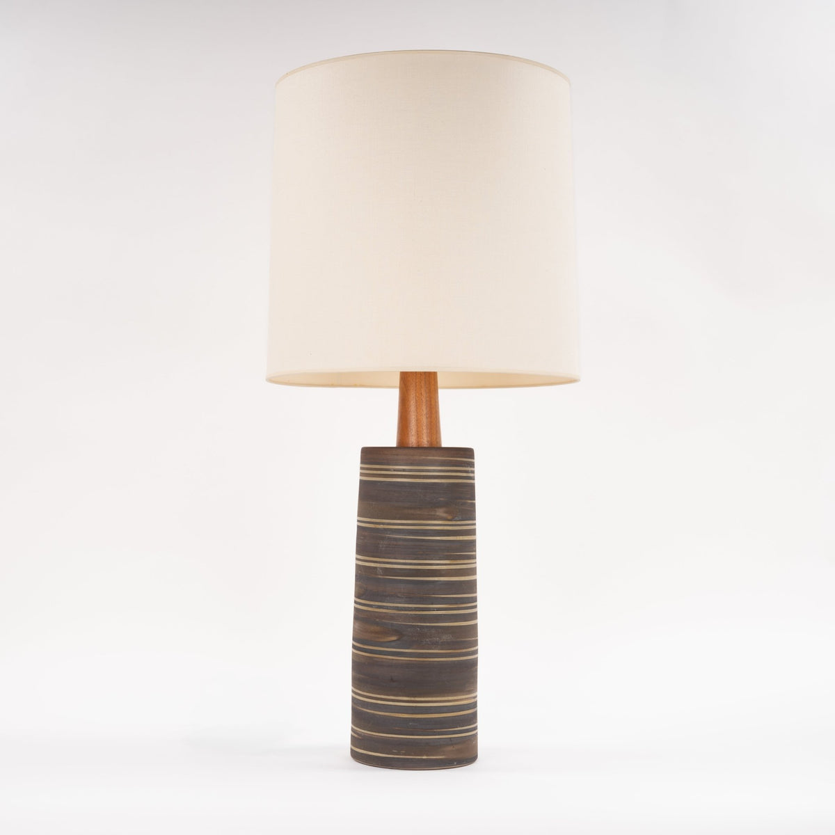 Gordon & Jane Martz Table Lamp with a dark striped ceramic base wooden stem and cream drum shade shown against a white background in mid century modern lighting style