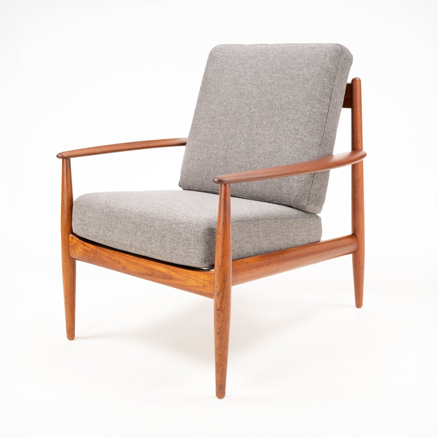 Wood-framed lounge chair with tapered legs and curved armrests, upholstered in soft light gray cushions