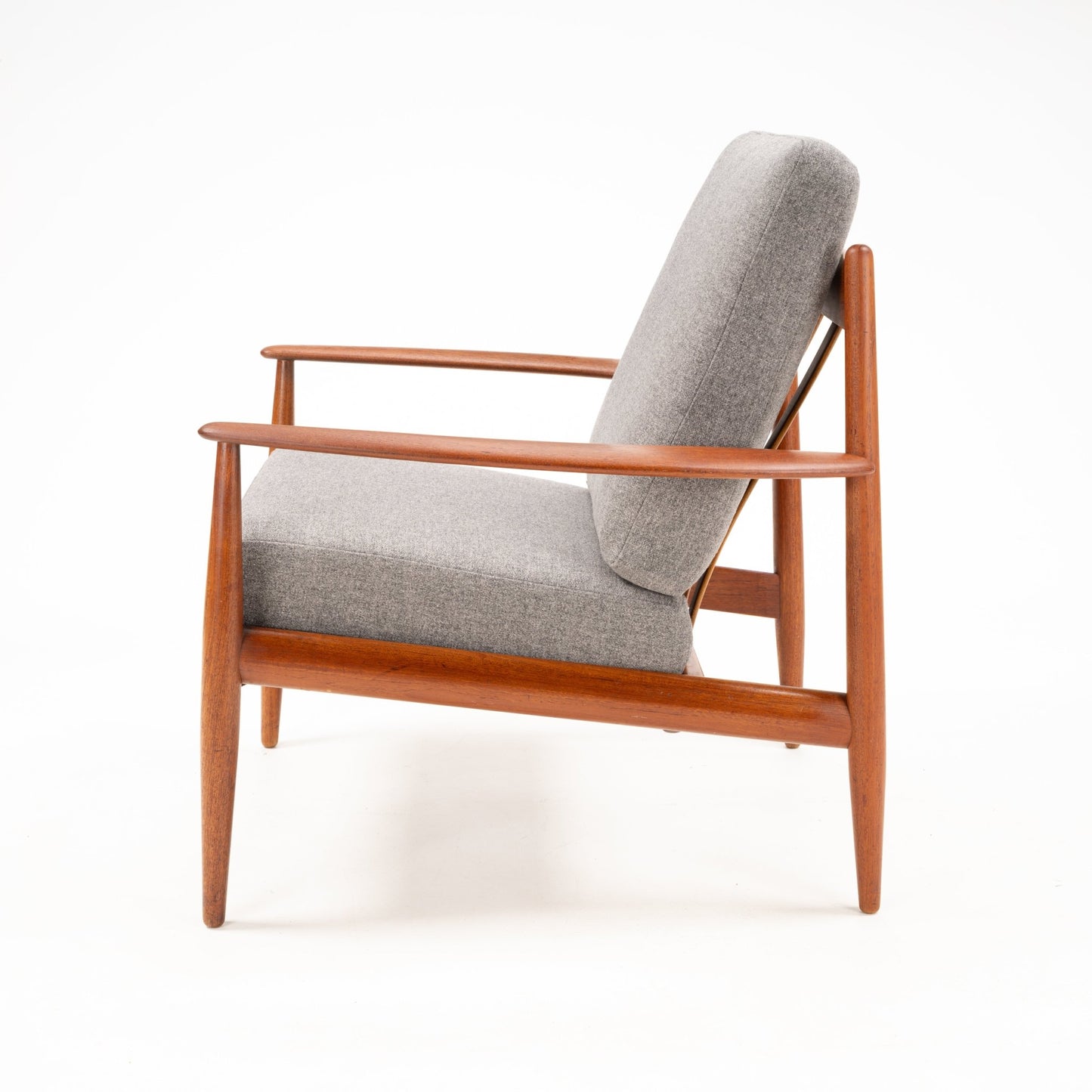 Side view of a mid-century modern wooden armchair with angled legs and gray upholstered cushions