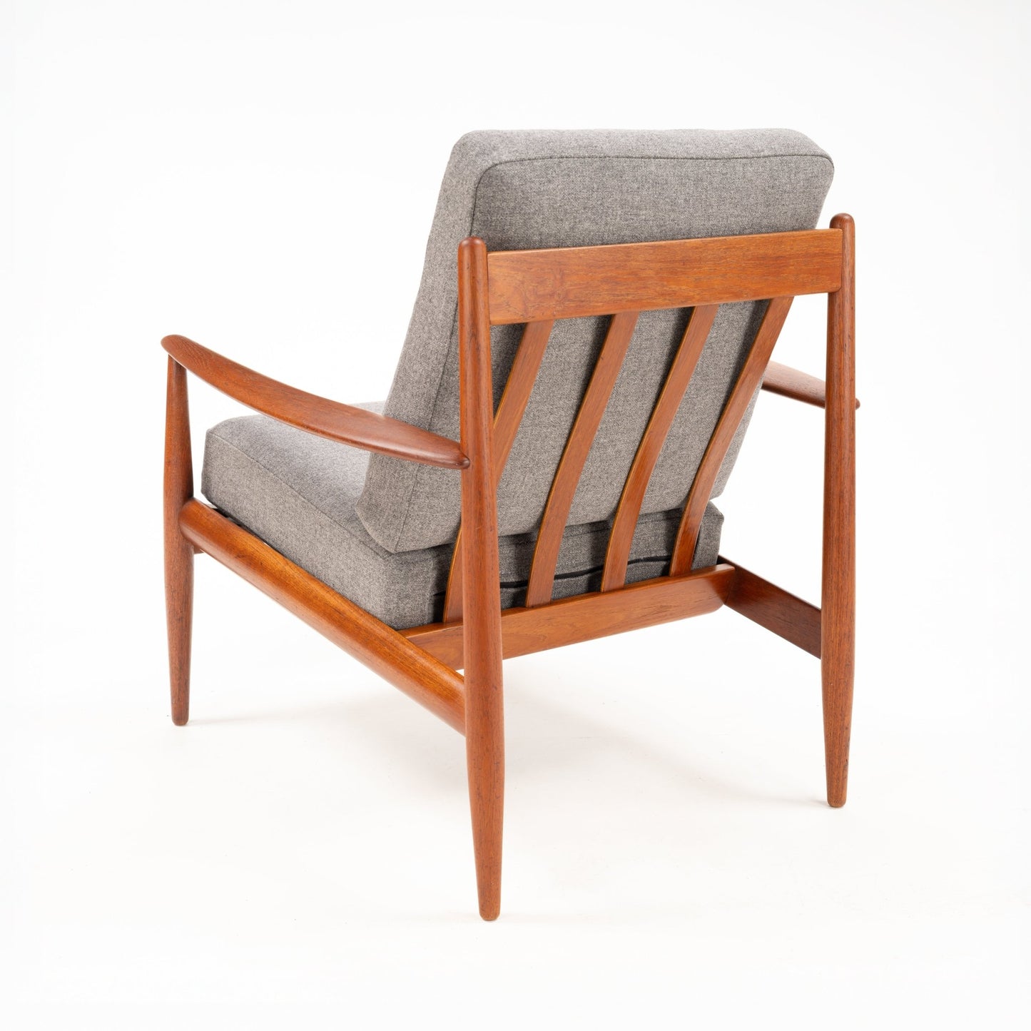Rear angle of a wooden mid-century armchair with gray cushions and distinctive slatted backrest design
