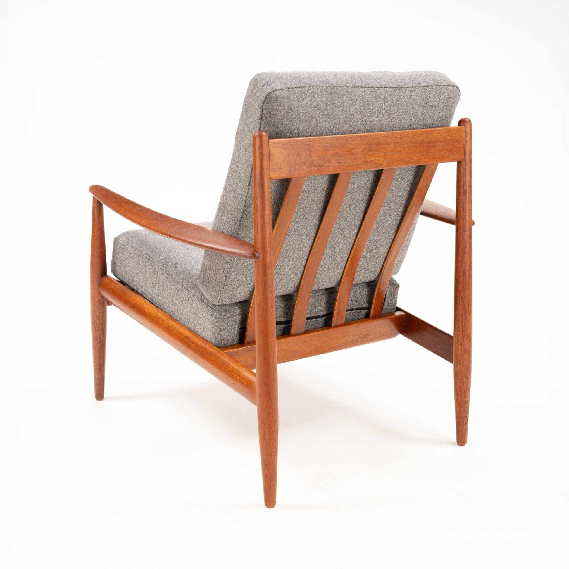 Rear angle of a wooden mid-century armchair with gray cushions and distinctive slatted backrest design