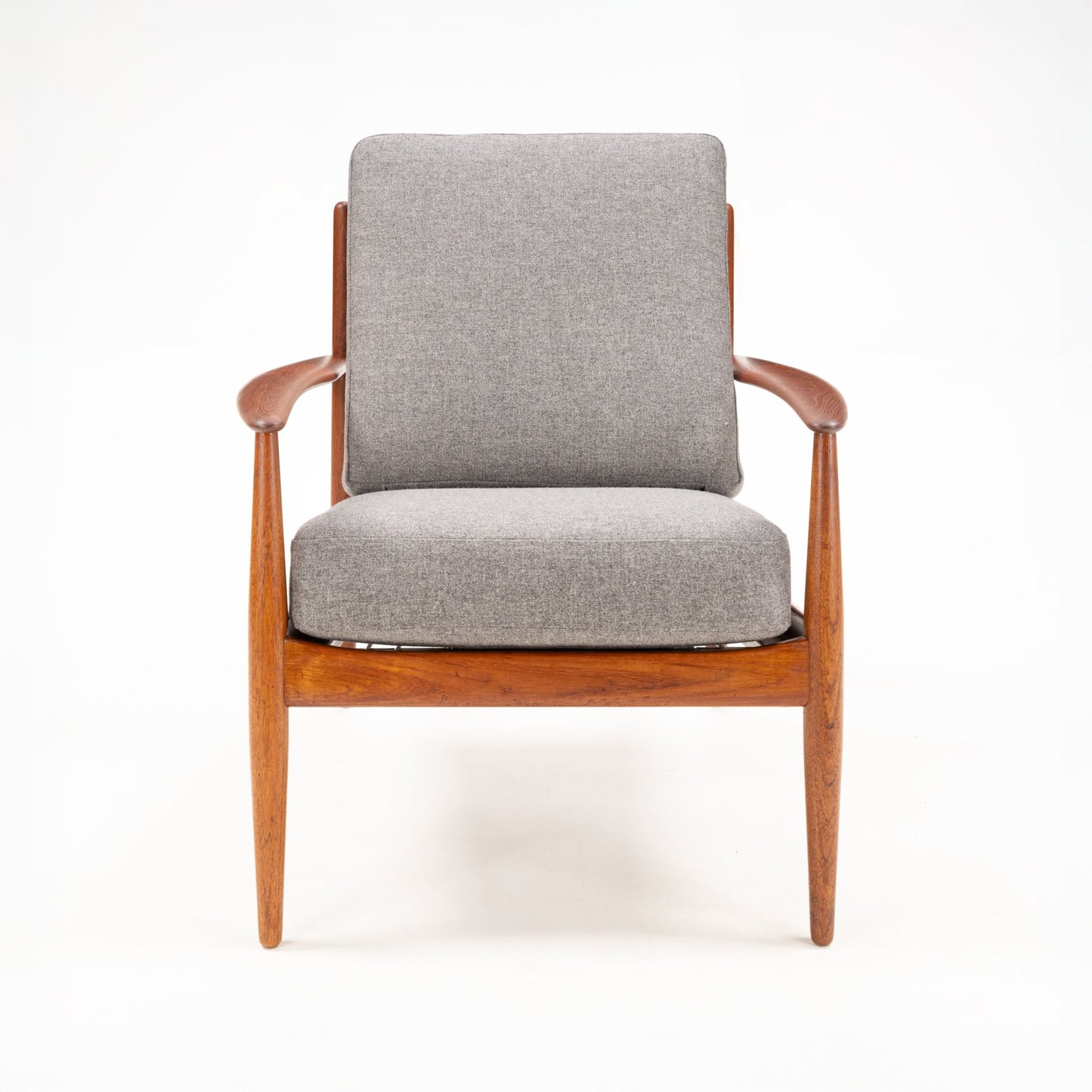 Armchair with sleek wooden frame and gently curved armrests upholstered in light gray fabric cushions