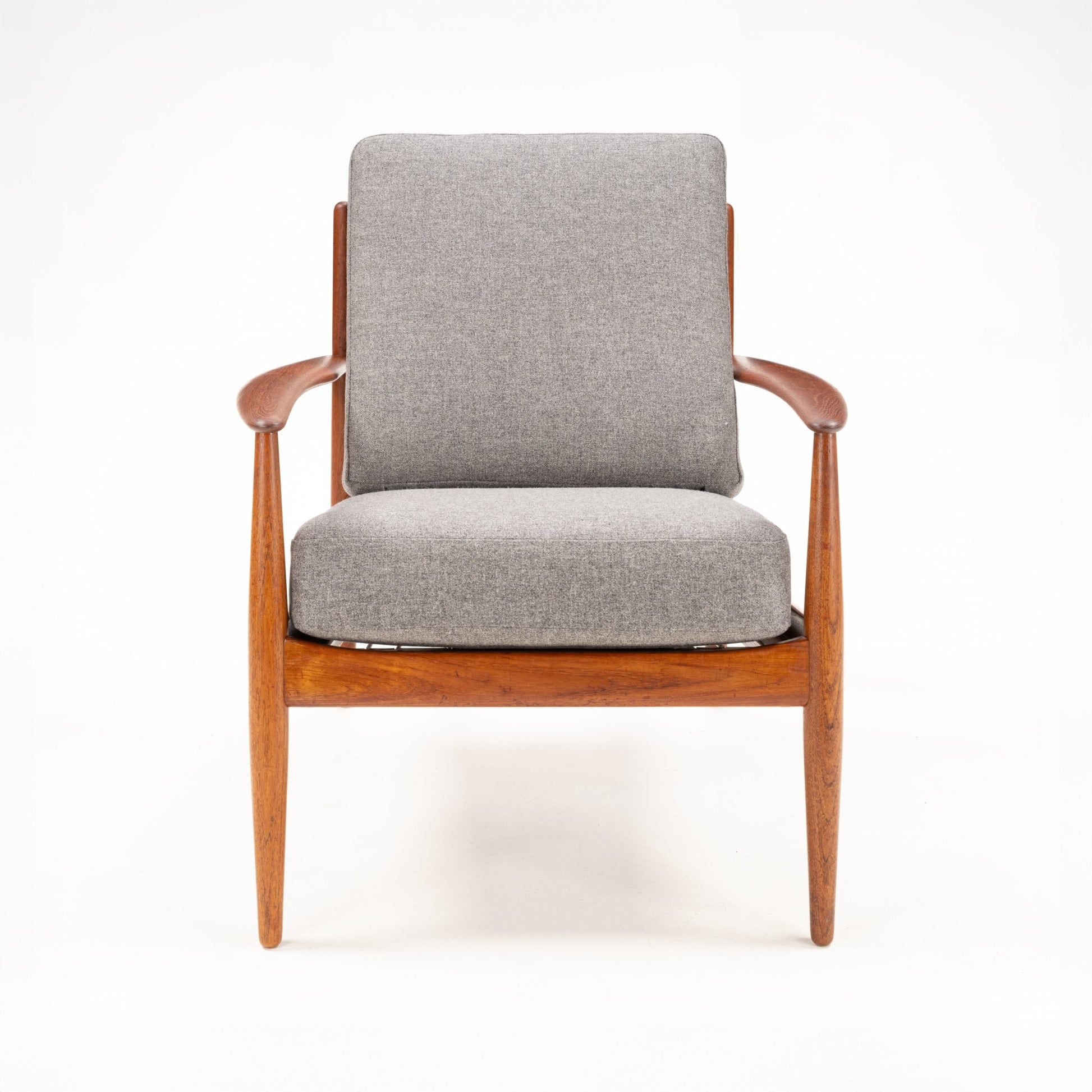 Armchair with sleek wooden frame and gently curved armrests upholstered in light gray fabric cushions