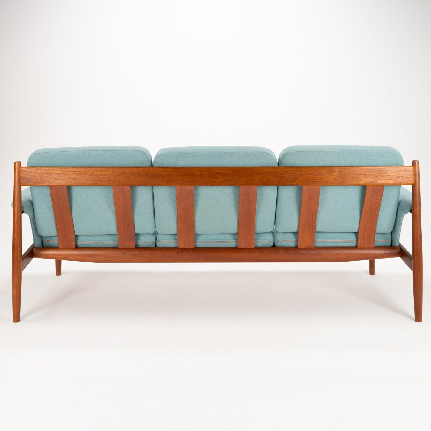 Grete Jalk Model 118 Teak Sofa featuring a sculpted teak frame with vertical slats and slender angled legs, upholstered in soft muted teal fabric, showcasing vintage Danish seating design.