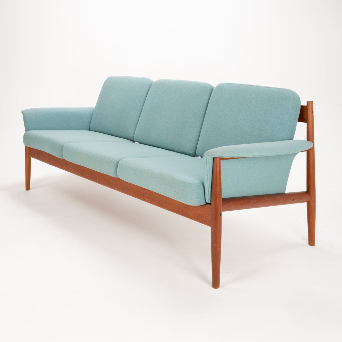 Grete Jalk Model 118 Teak Sofa with a slender teak frame and angled legs, featuring soft light teal cushions and armrests, exemplifying vintage Danish mid century modern seating.