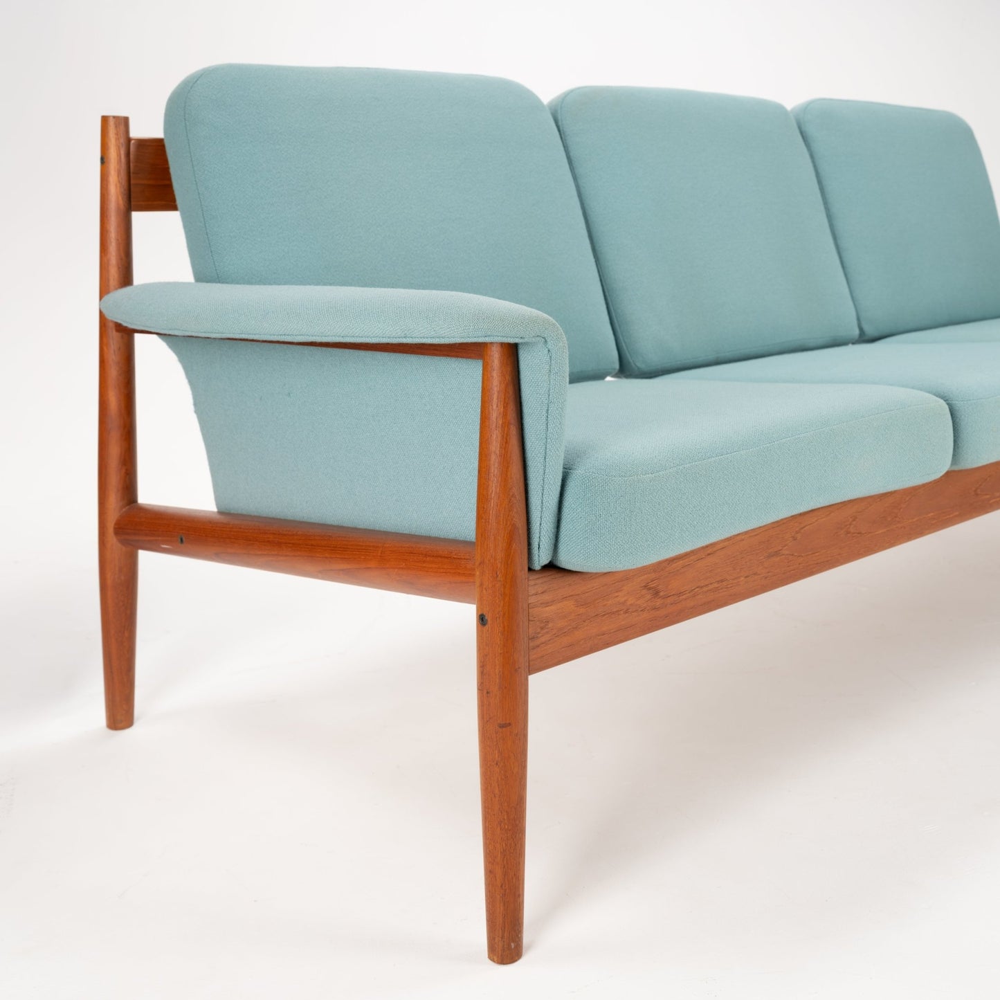 Grete Jalk Model 118 Teak Sofa featuring a refined teak frame with gently tapered legs and armrests, upholstered in soft muted blue fabric, exemplifying vintage Danish mid century modern seating.