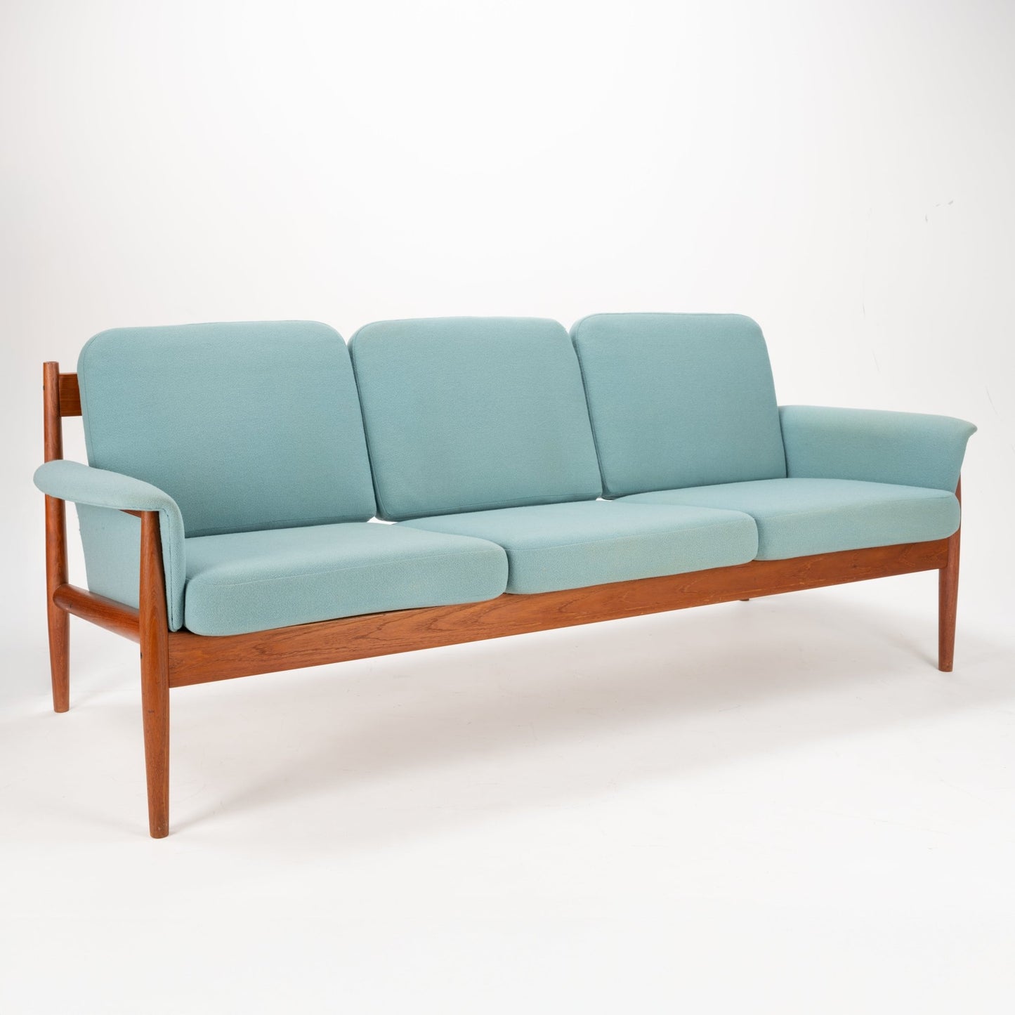 Grete Jalk Model 118 Teak Sofa featuring a clean-lined teak frame with gently curved armrests and soft muted blue cushions, embodying elegant mid century modern seating design.