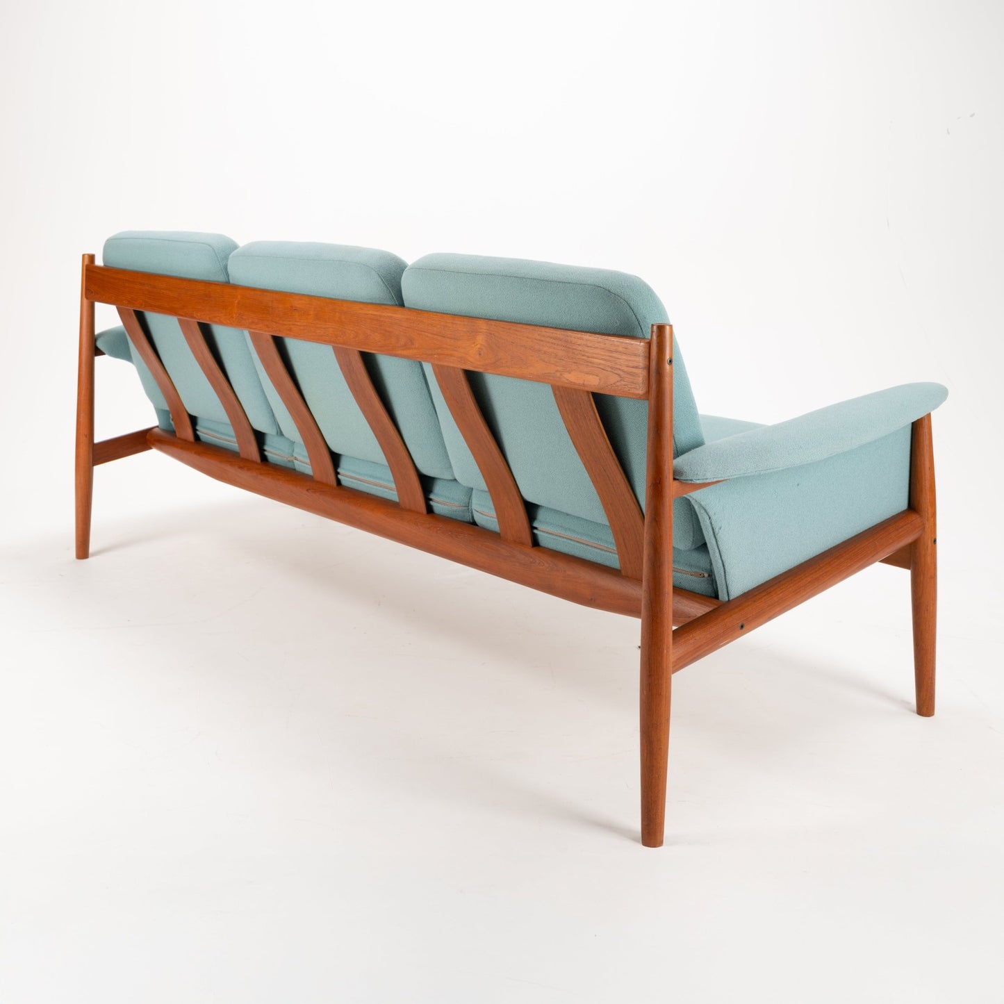 Grete Jalk Model 118 Teak Sofa with an exposed teak frame featuring angled supports and tapered legs, upholstered in soft muted green fabric, reflecting vintage Danish mid century modern seating.
