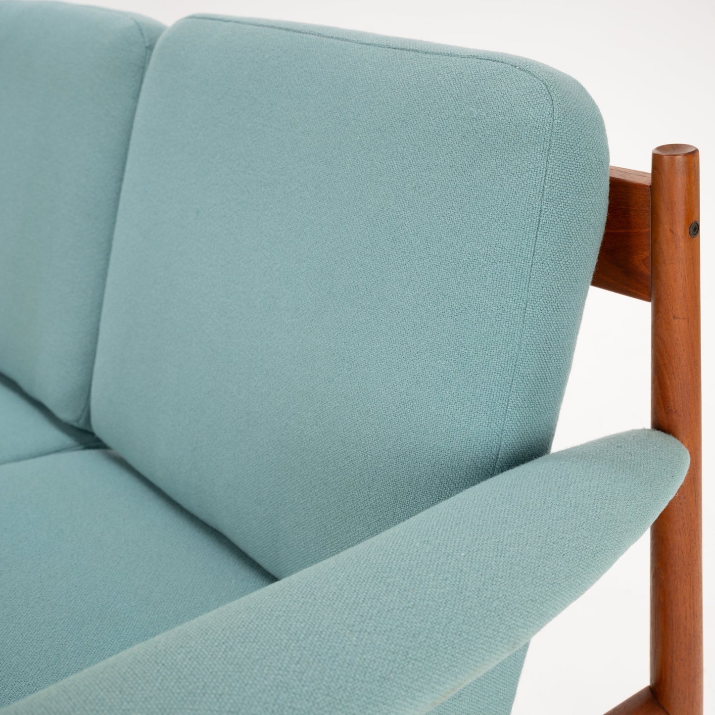 Grete Jalk Model 118 Teak Sofa featuring a smooth teak frame with cylindrical supports and tapered armrests, upholstered in soft muted aqua fabric, highlighting vintage Danish mid century modern seating.