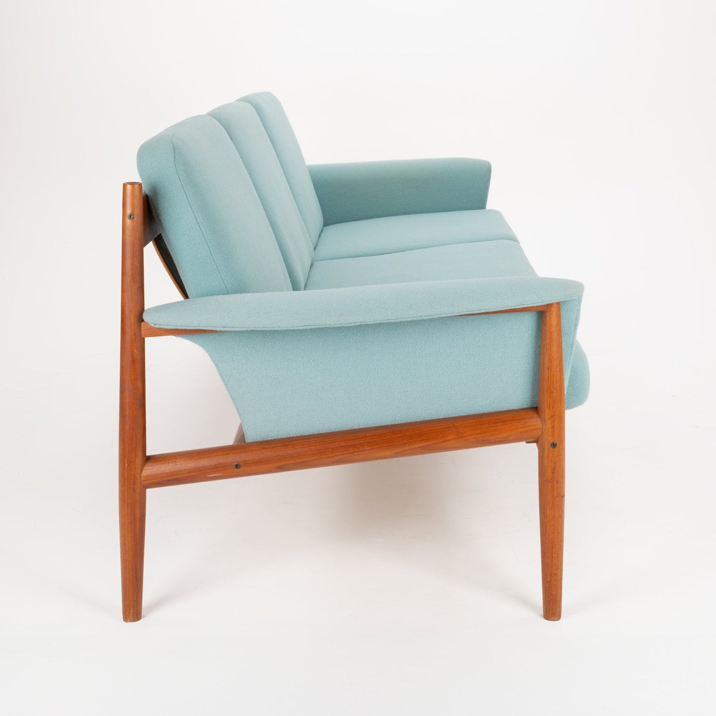 Grete Jalk Model 118 Teak Sofa featuring a sculpted teak frame with angled legs and armrests, upholstered in soft muted teal fabric, exemplifying vintage Danish mid century modern seating.
