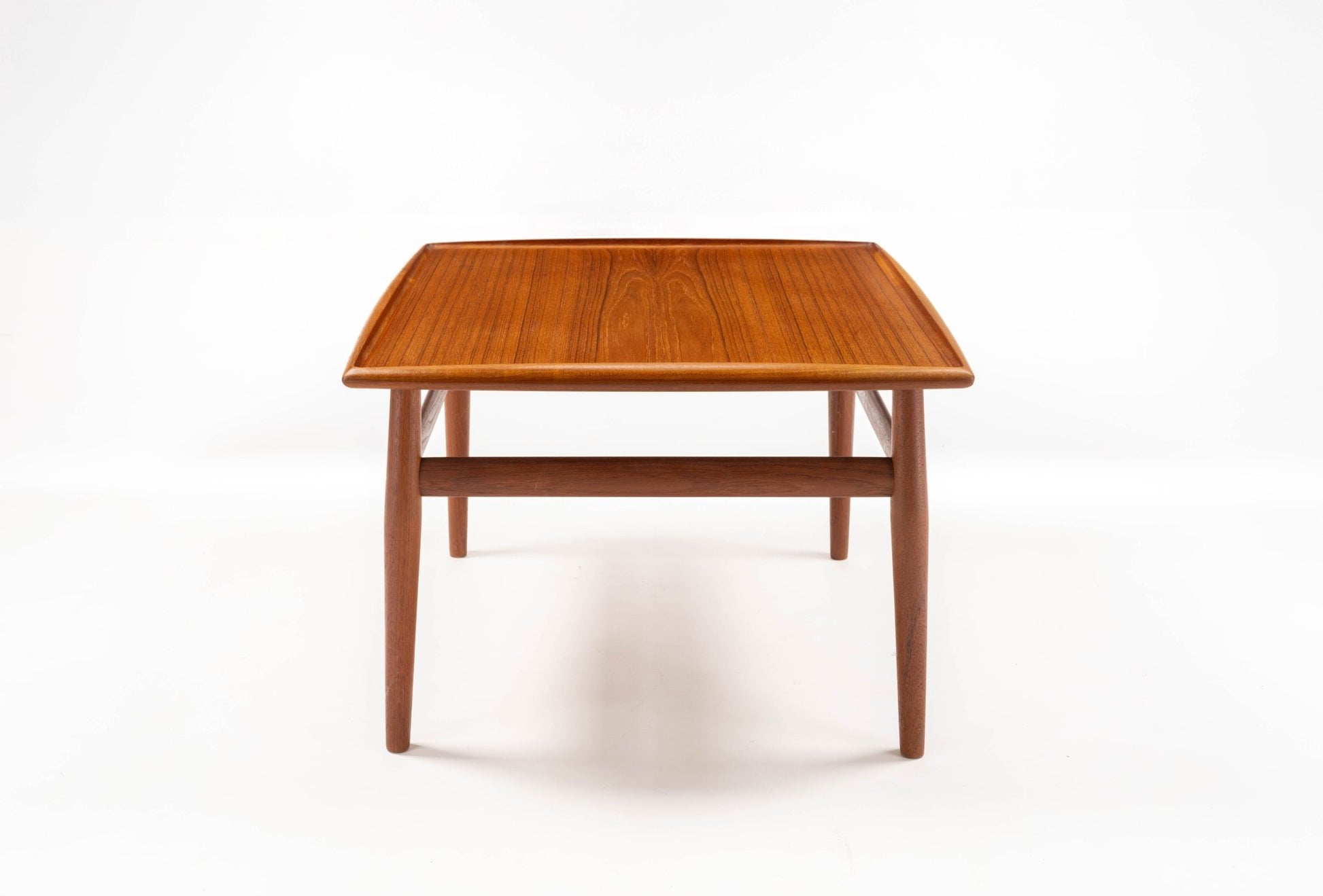 Grete Jalk mid-century modern teak square side table with raised edge and turned legs on white background