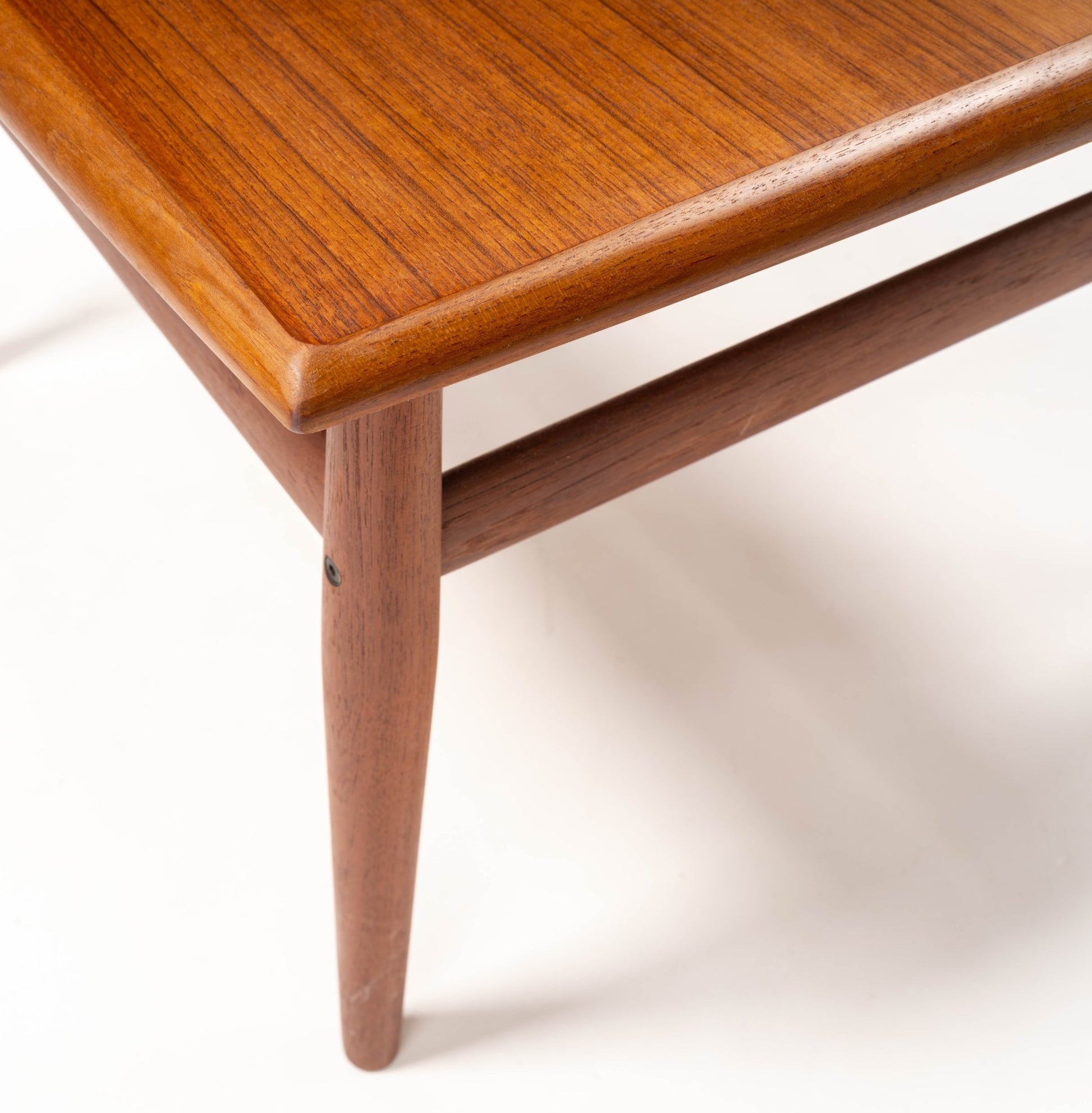 Close-up of Grete Jalk mid-century modern teak side table with square top, raised edges, turned legs, and stretcher detail.