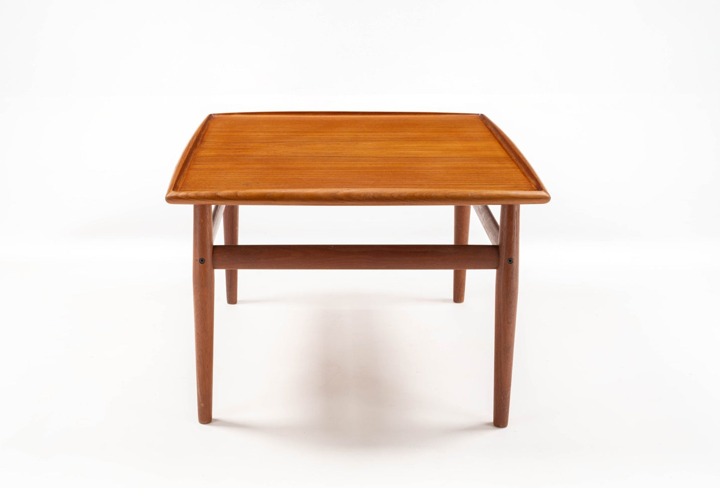 Square mid-century modern teak side table with raised edge and turned legs connected by stretchers on white background