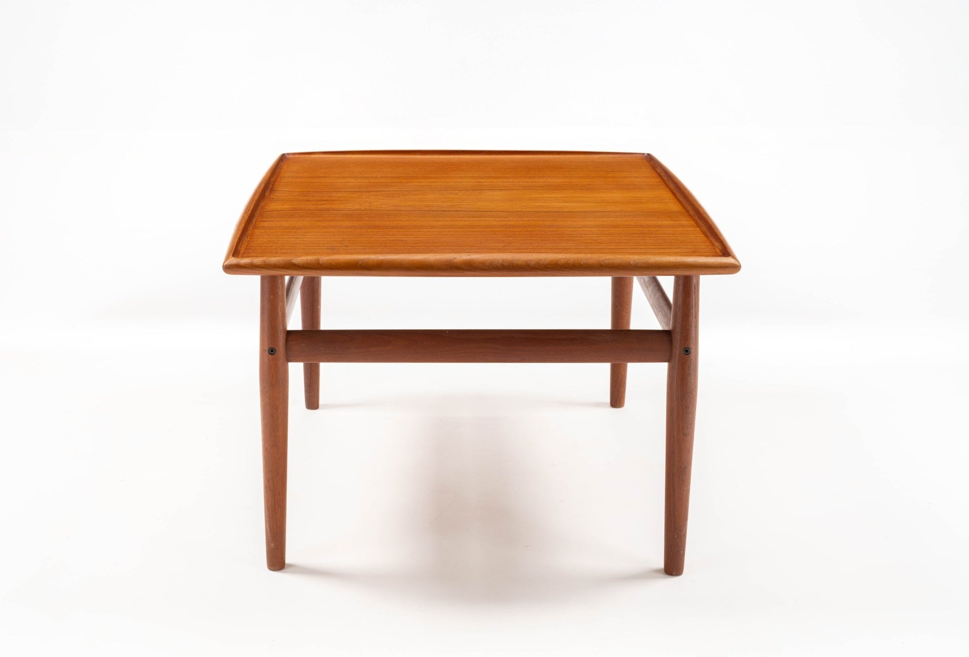 Square mid-century modern teak side table with raised edge and turned legs connected by stretchers on white background