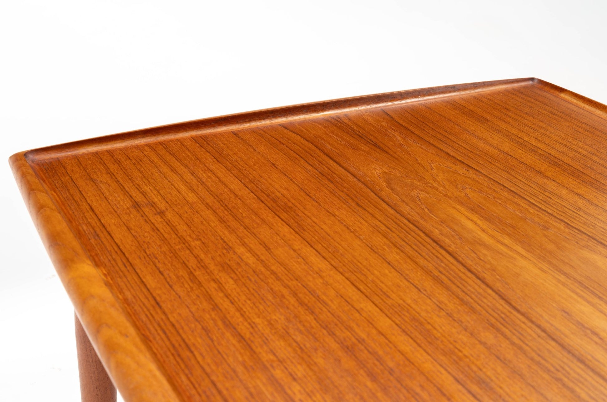 Close-up of Grete Jalk teak square side table top with raised frame and visible wood grain in warm finish
