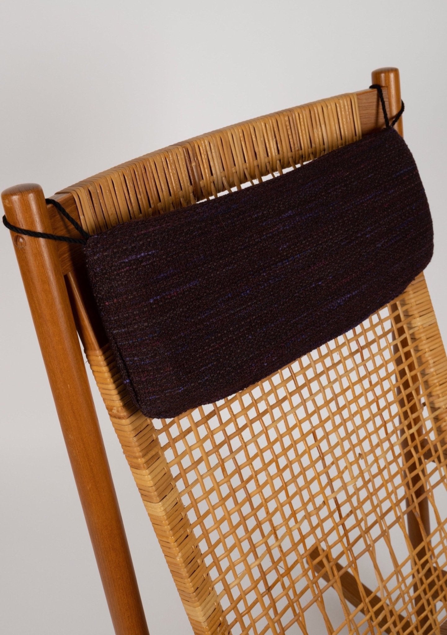 Detail of Hans Olsen 1960s Danish teak and woven cane rocking chair with dark fabric headrest cushion