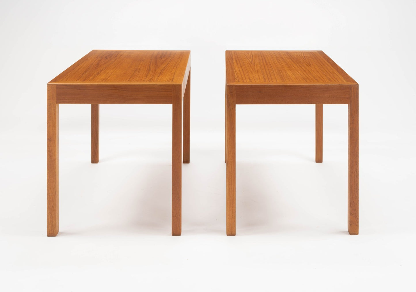Pair of Hans Wegner Danish teak side tables with minimalist rectangular tops and slender legs on white background