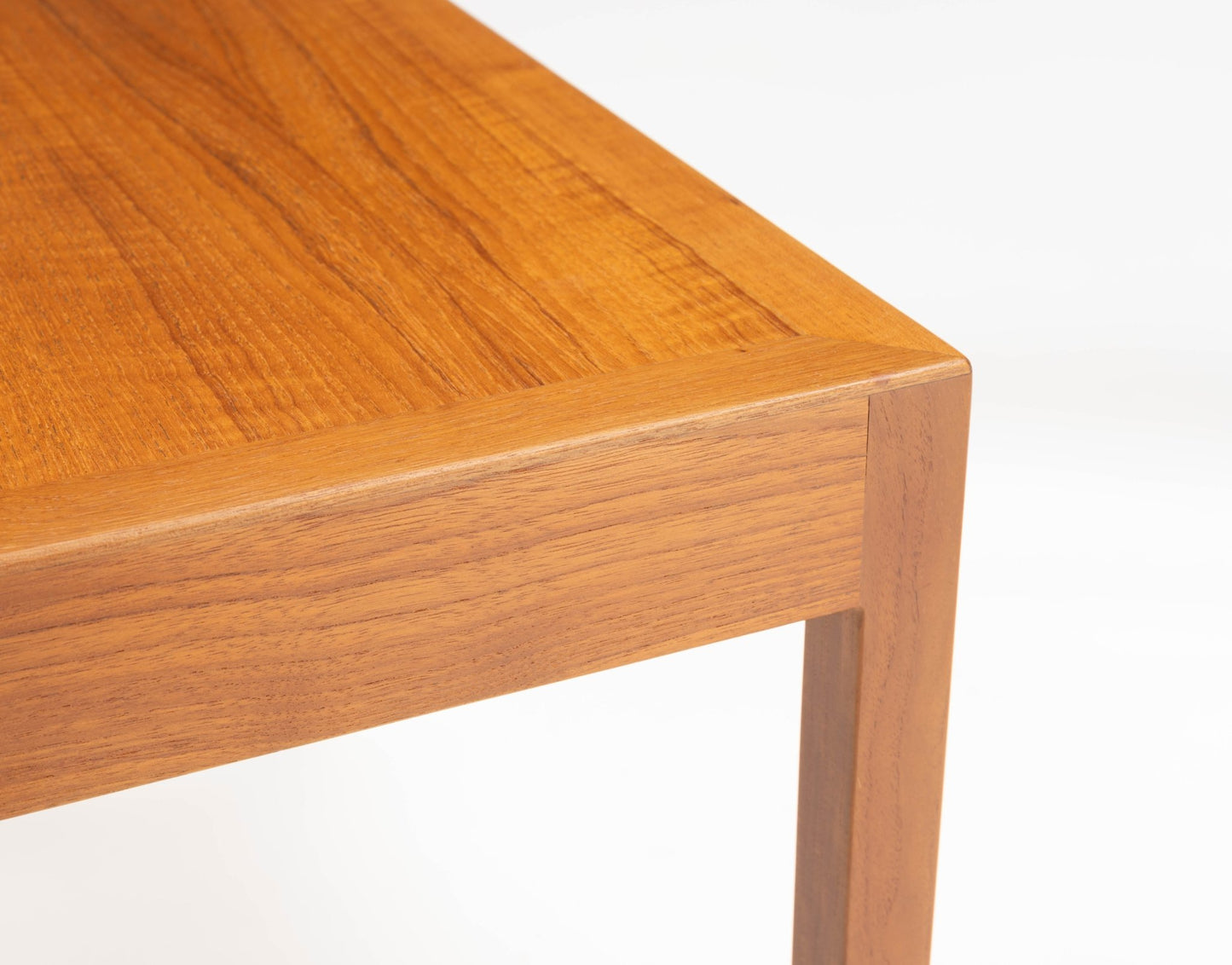Close-up of Danish teak side table corner with clean minimalist lines and smooth wood grain finish