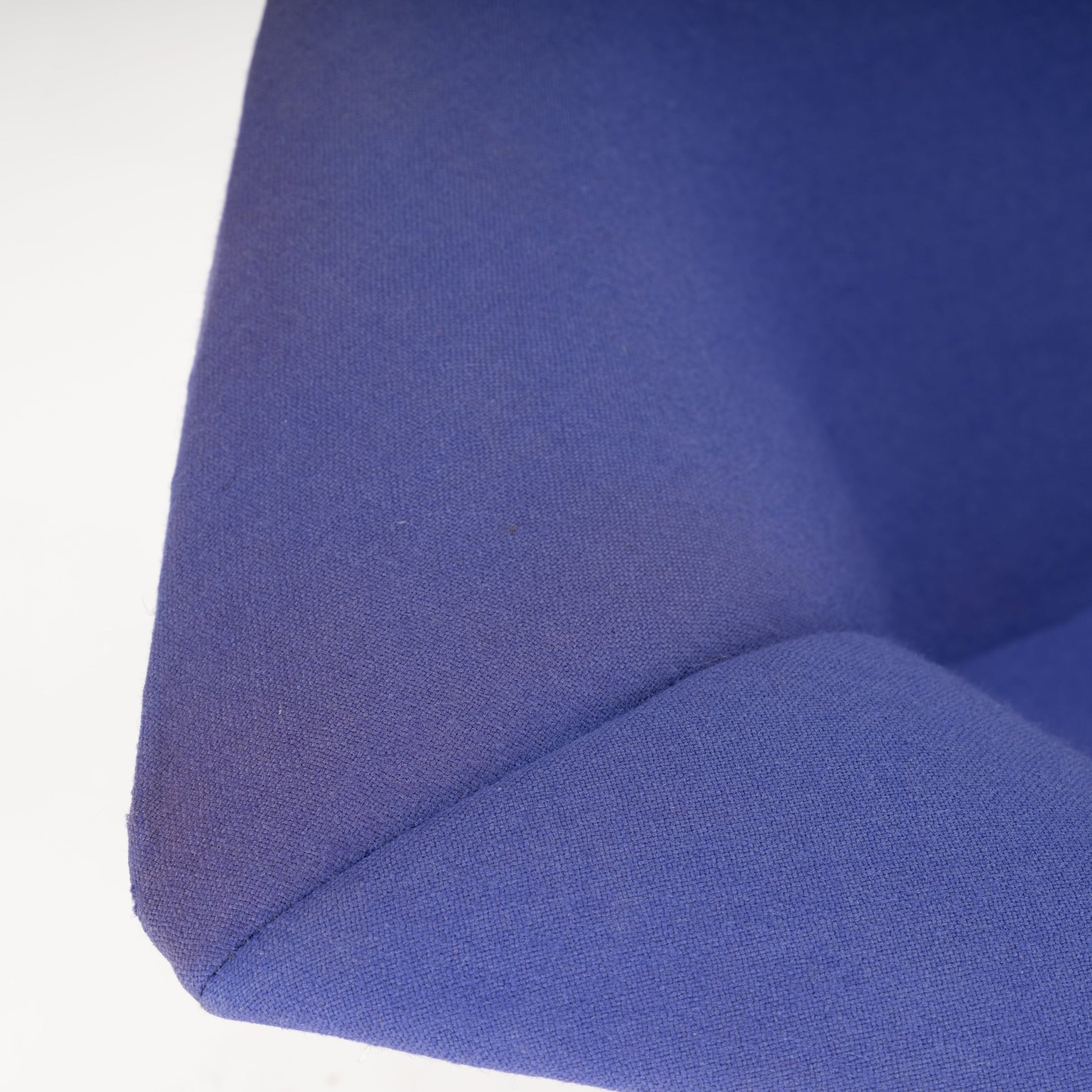Close-up of a textured fabric chair corner in a rich blue color with visible stitching and soft cushioning
