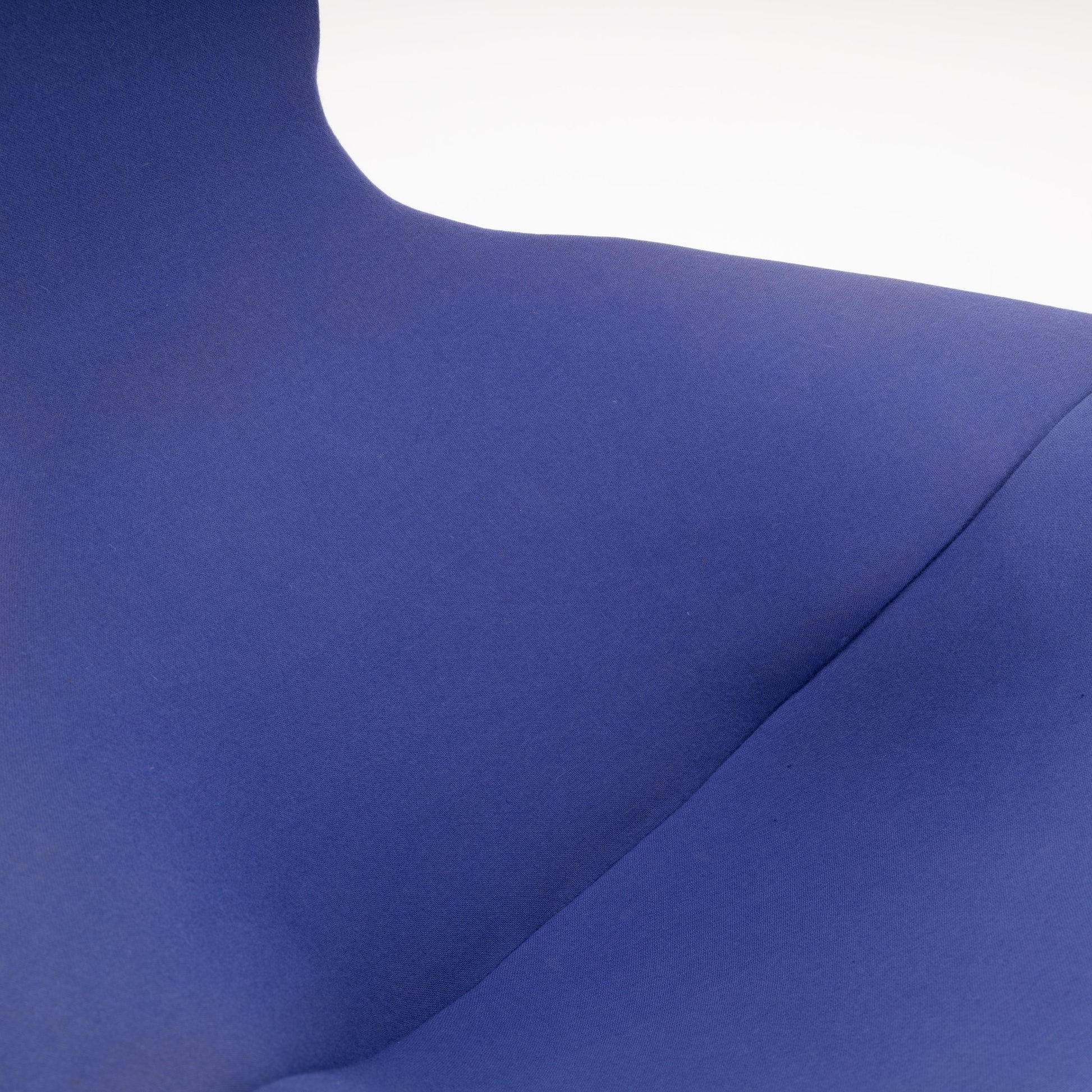 Close-up of smooth blue fabric upholstery on a curved chair seat without visible seams or stitching