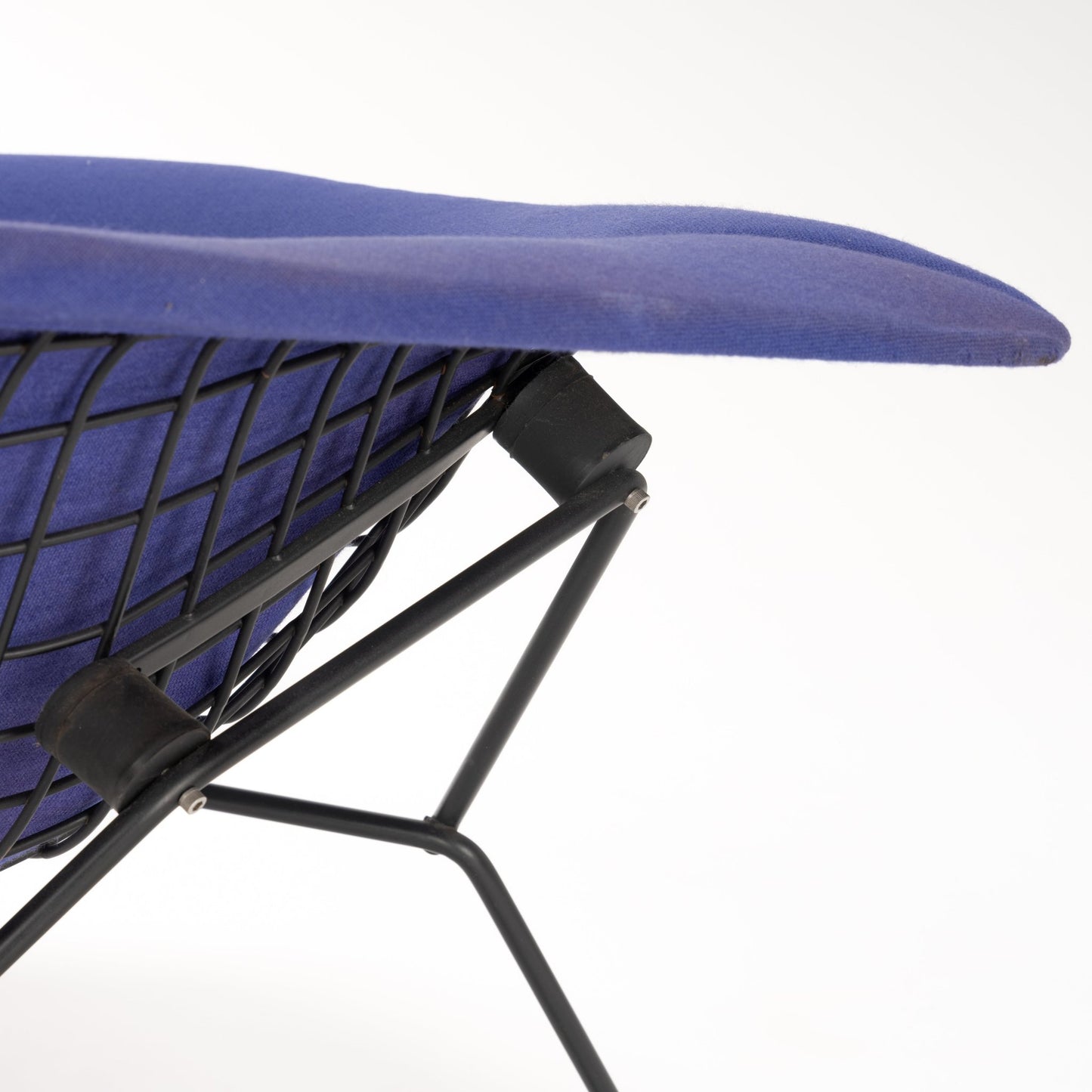 Close-up of a lounge chair showing curved blue fabric seat and black metal wireframe base with diagonal support bars