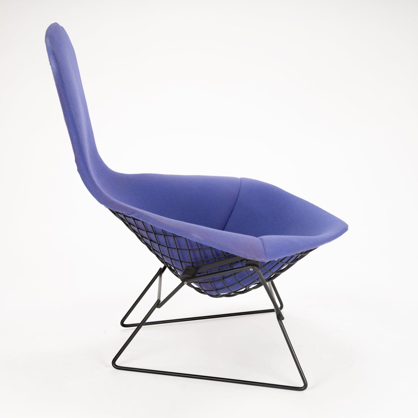 Side profile of a lounge chair featuring deep purple fabric upholstery and a black geometric metal wireframe base