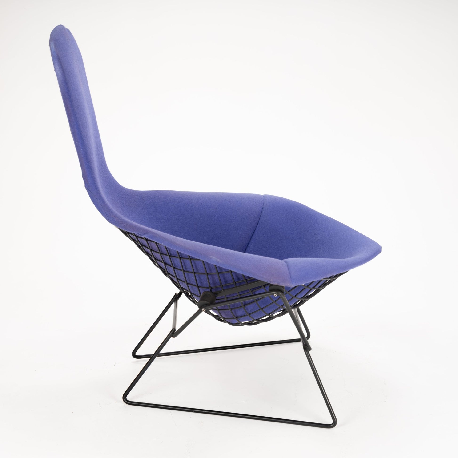 Side profile of a lounge chair featuring deep purple fabric upholstery and a black geometric metal wireframe base