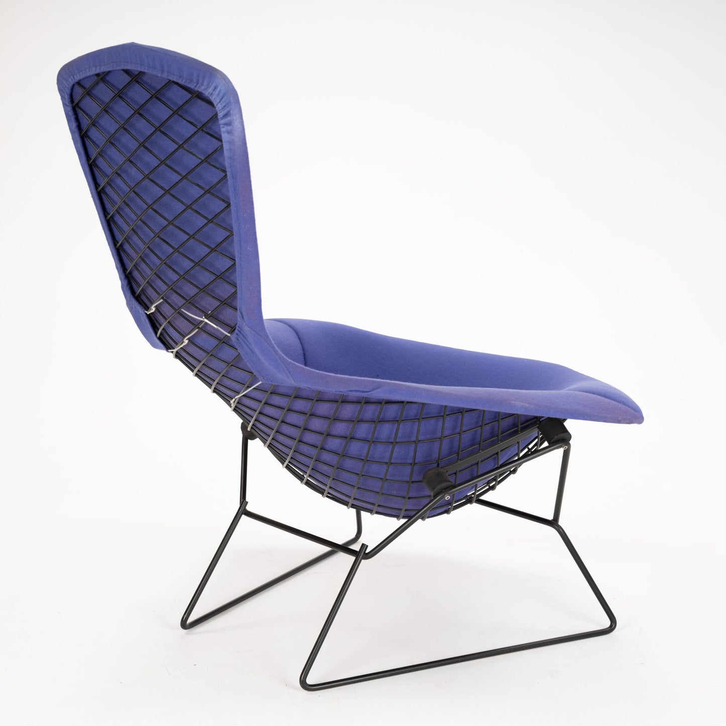 Side view of a lounge chair with deep blue cushioning and black wireframe lattice base and backrest support