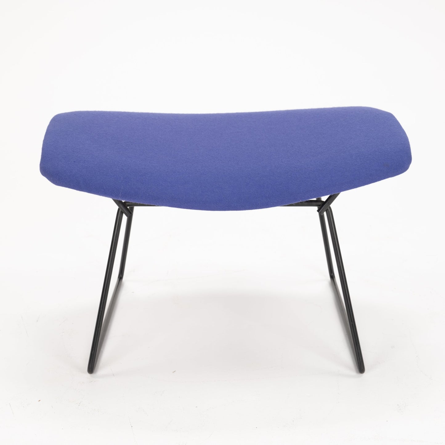 Low-profile stool with a curved blue upholstered seat and angled black metal legs on a white background