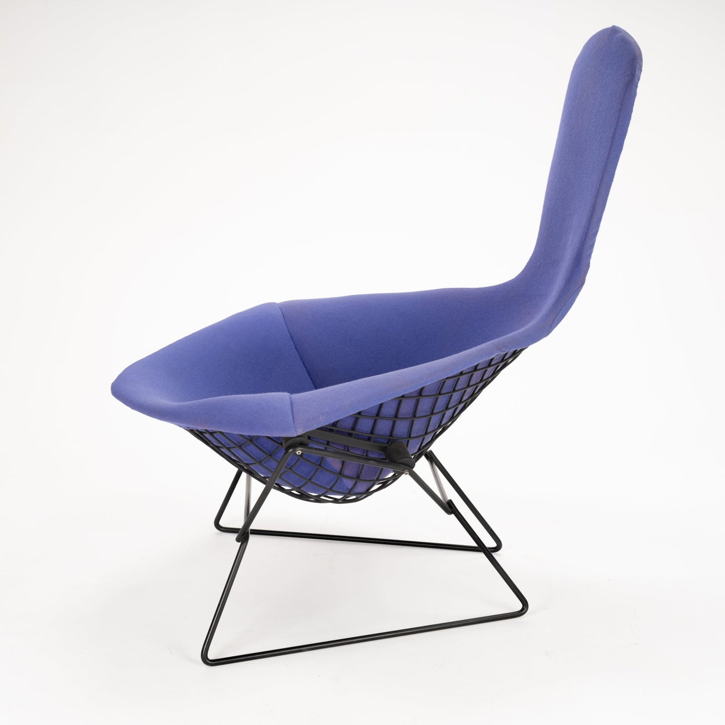 Modern lounge chair with blue fabric upholstery and black metal wireframe base with mesh design beneath seat
