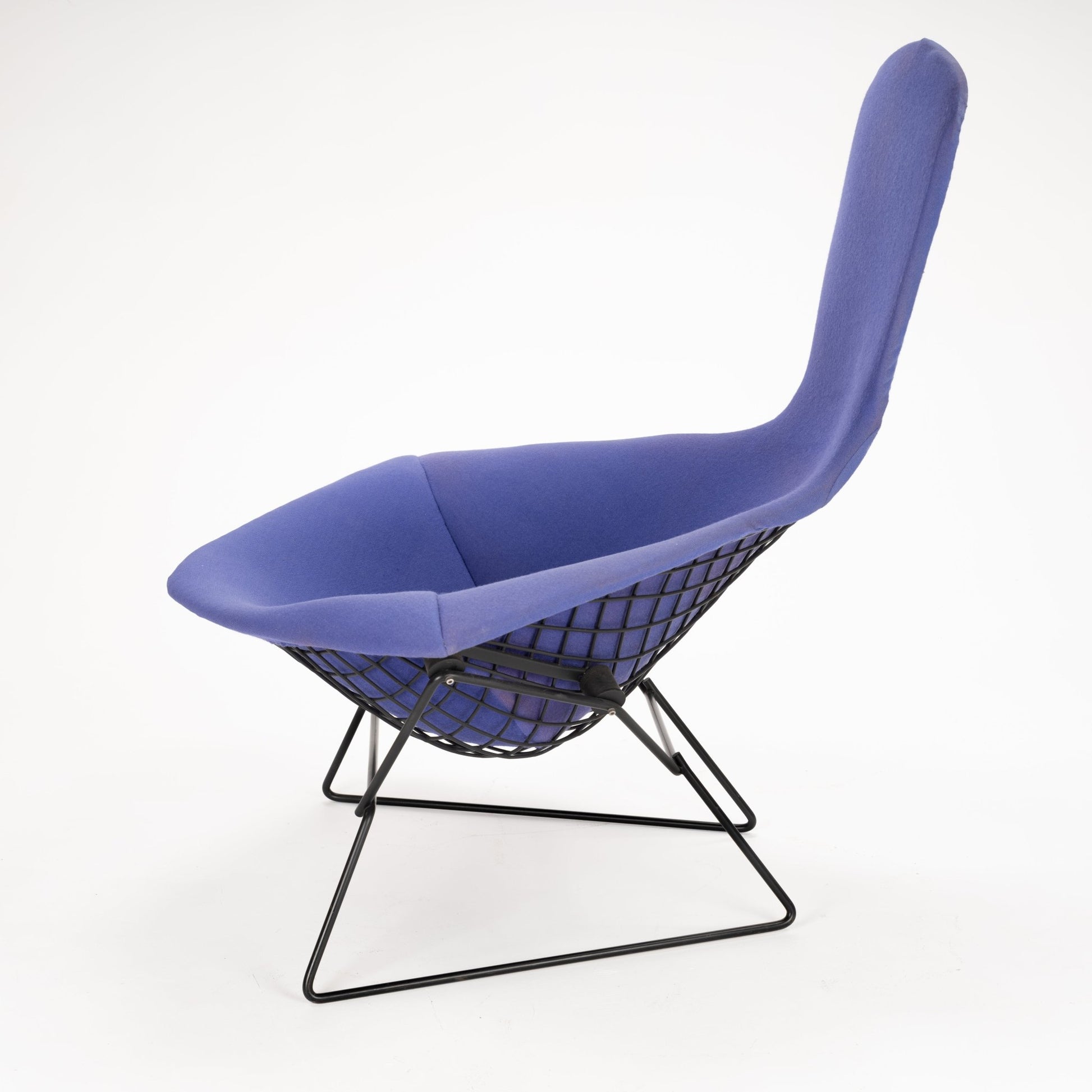 Modern lounge chair with blue fabric upholstery and black metal wireframe base with mesh design beneath seat