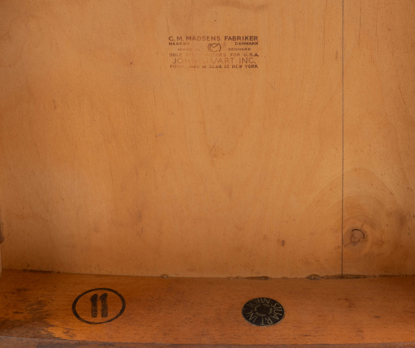 Close-up of underside of mid-century modern wooden chair showing factory stamps and markings on beech wood.
