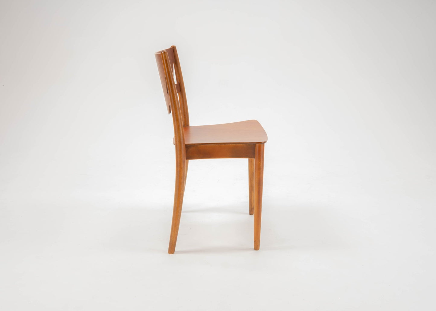 Side view of mid-century modern Hvidt & Molgaard desk chair with curved back and tapered teak legs on white background