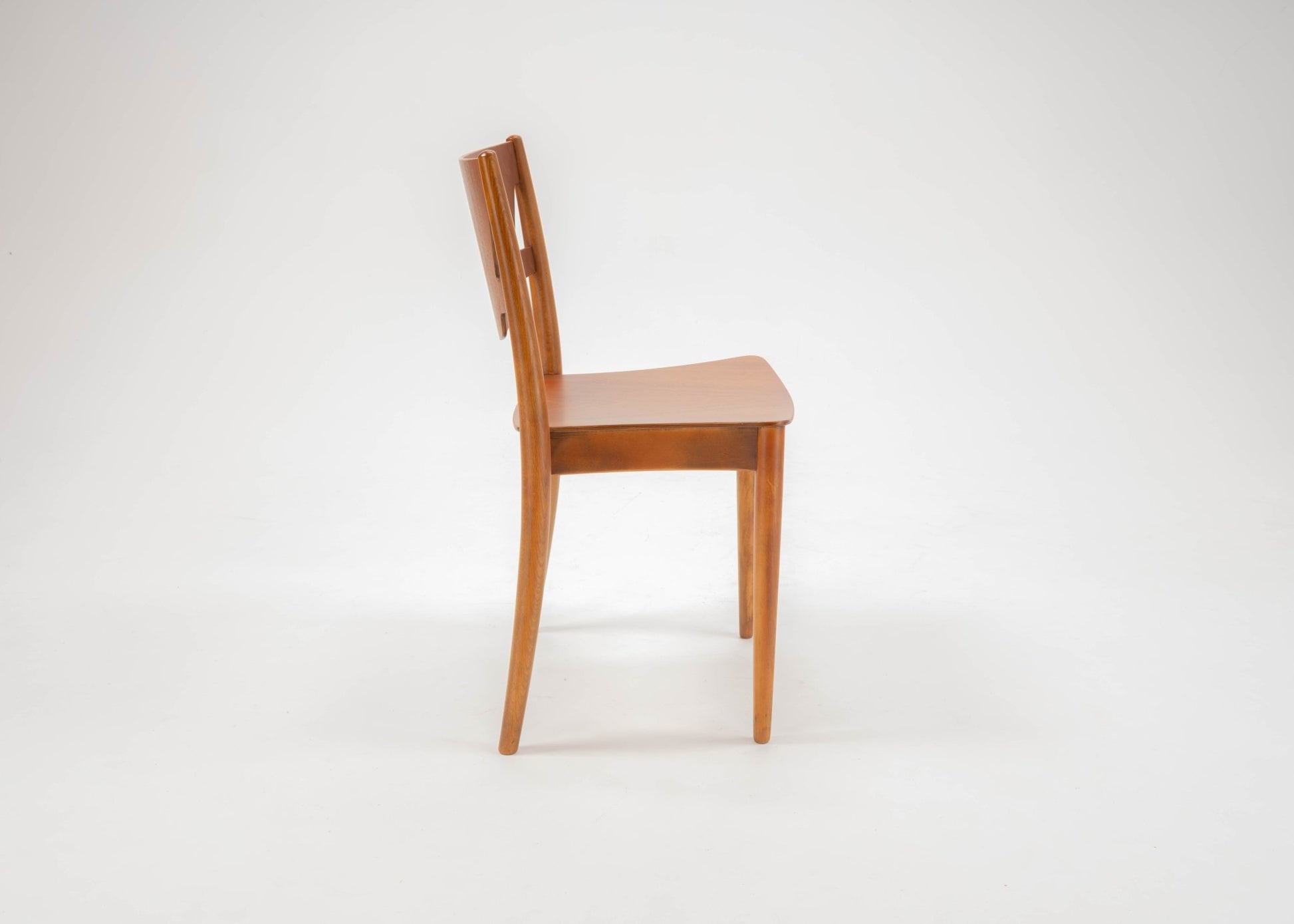Side view of mid-century modern Hvidt & Molgaard desk chair with curved back and tapered teak legs on white background