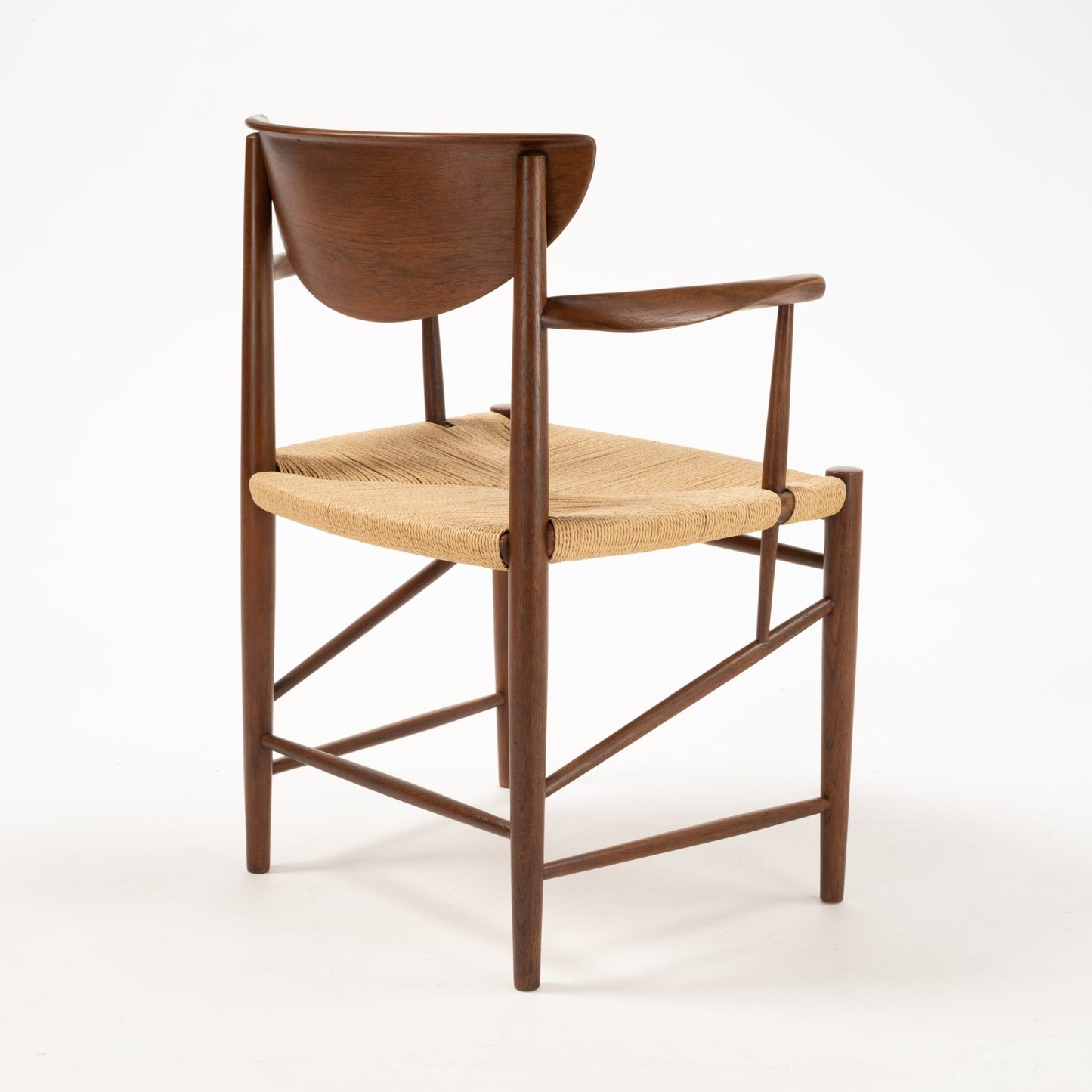 Rear angle of Hvidt & Molgaard Model 317 chair with sculpted teak backrest and woven natural fiber seat on slender wood frame